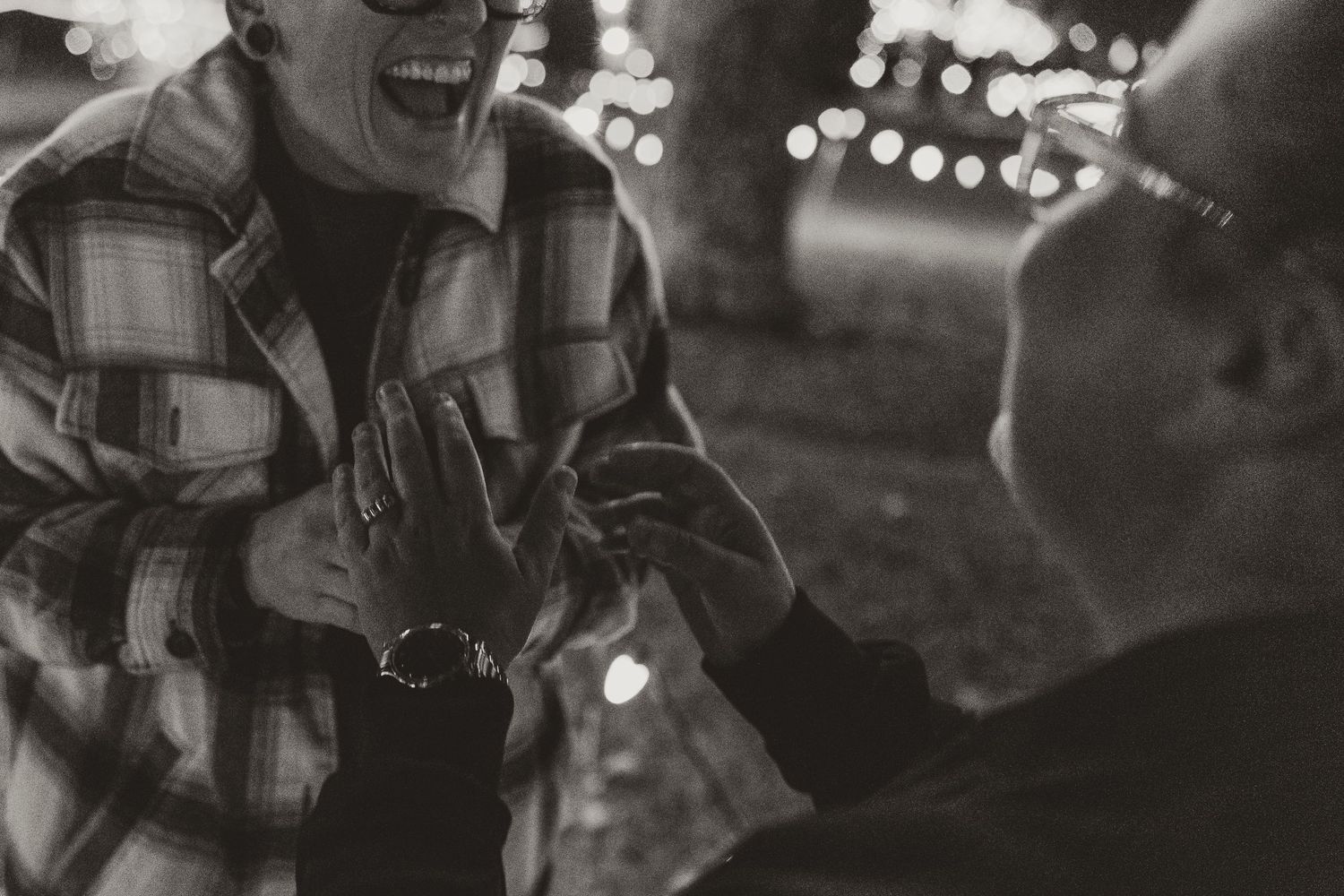 A candid black and white photo of people sharing a joyful moment together with bokeh lights in the background.