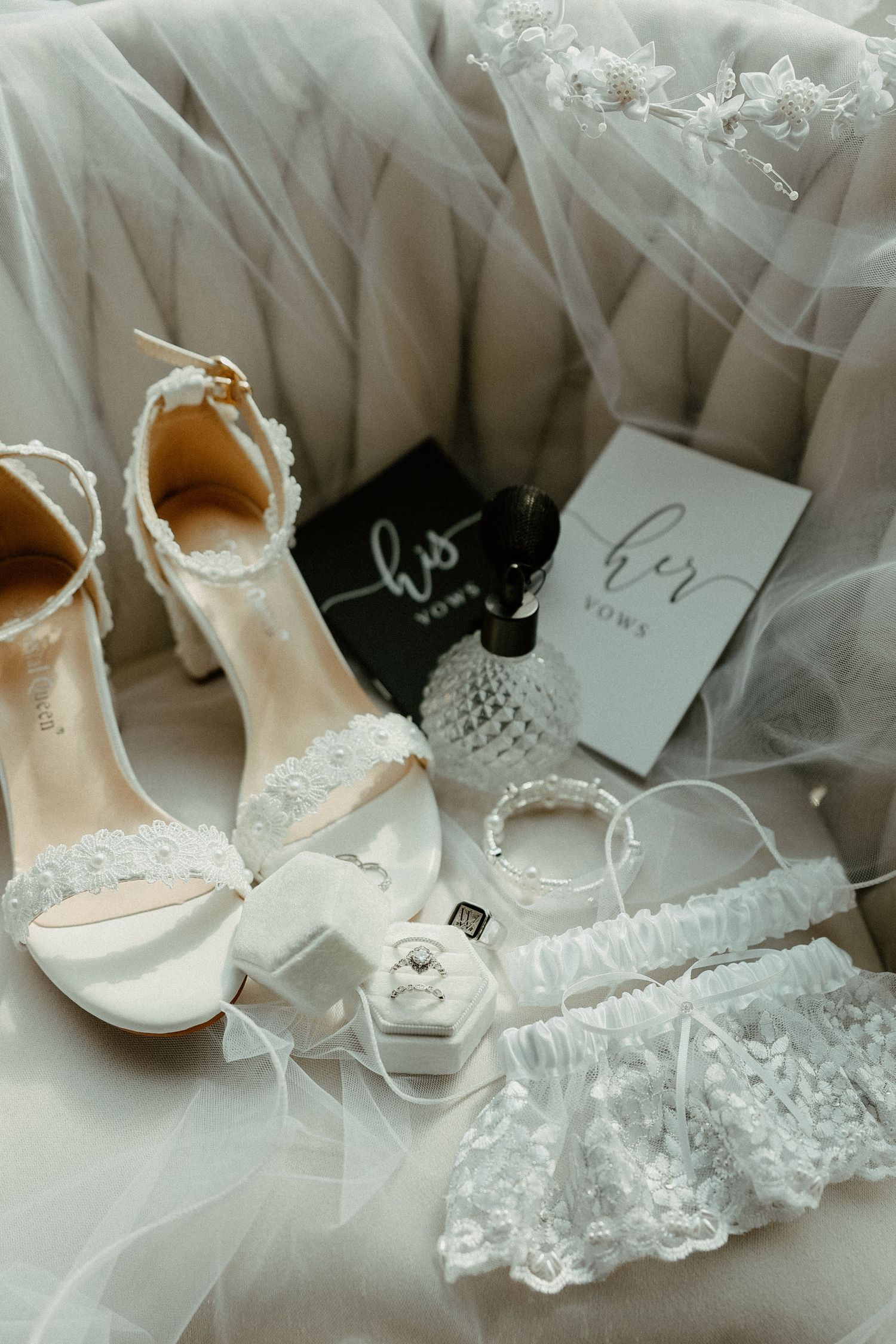 White lace bridal accessories including heels, garter, veil and wedding details on soft tulle fabric.
