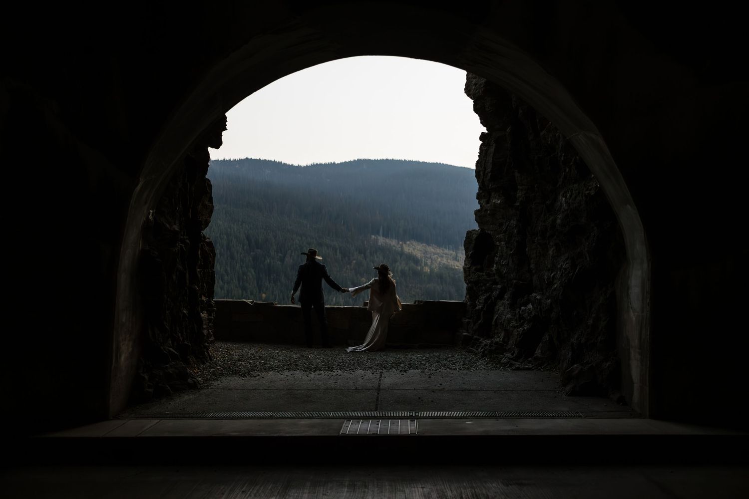 Silhouettes visible through stone archways at dusk in a mountainous setting.