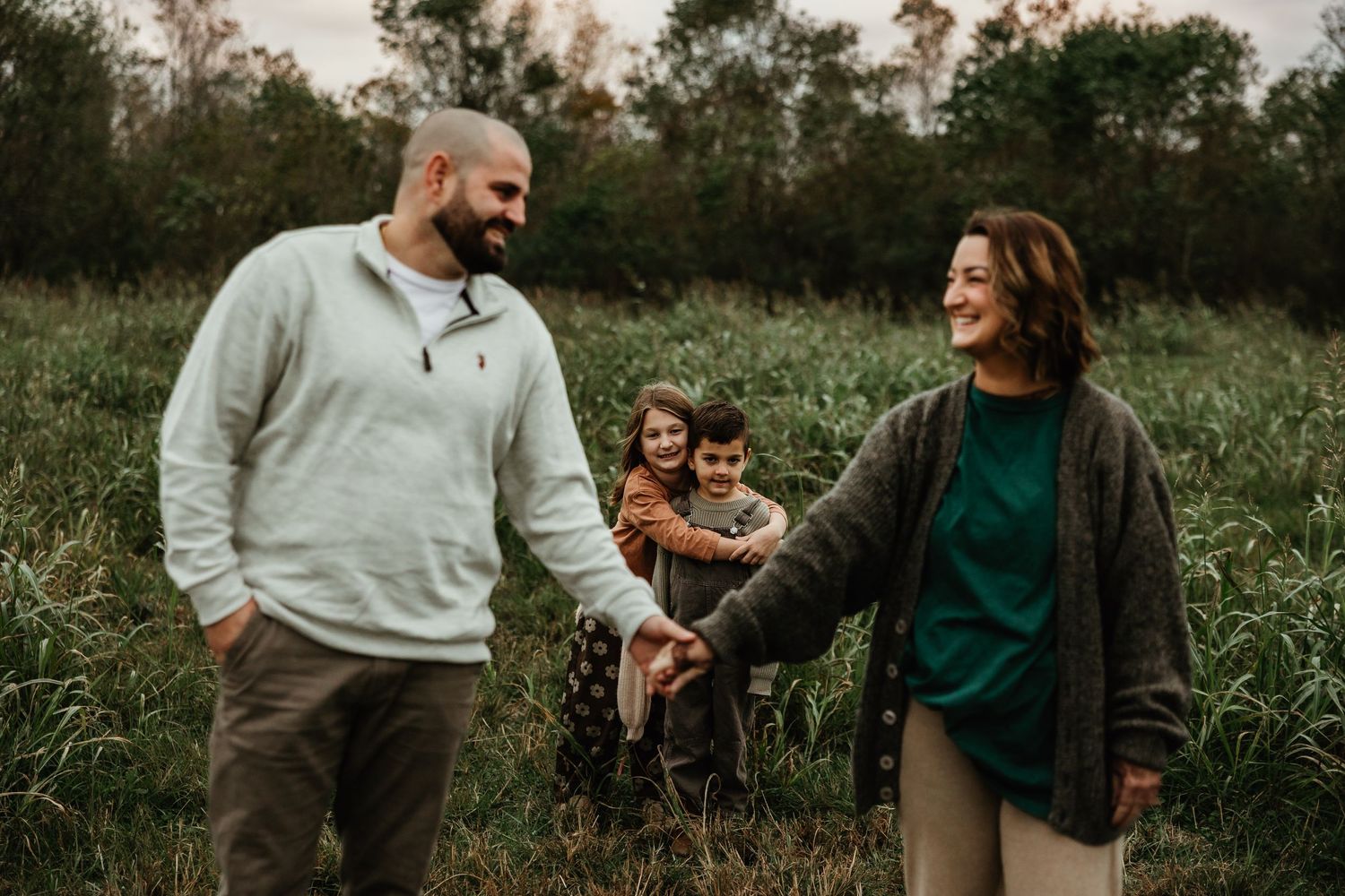 A family enjoying a casual moment together in a natural field setting during golden hour.