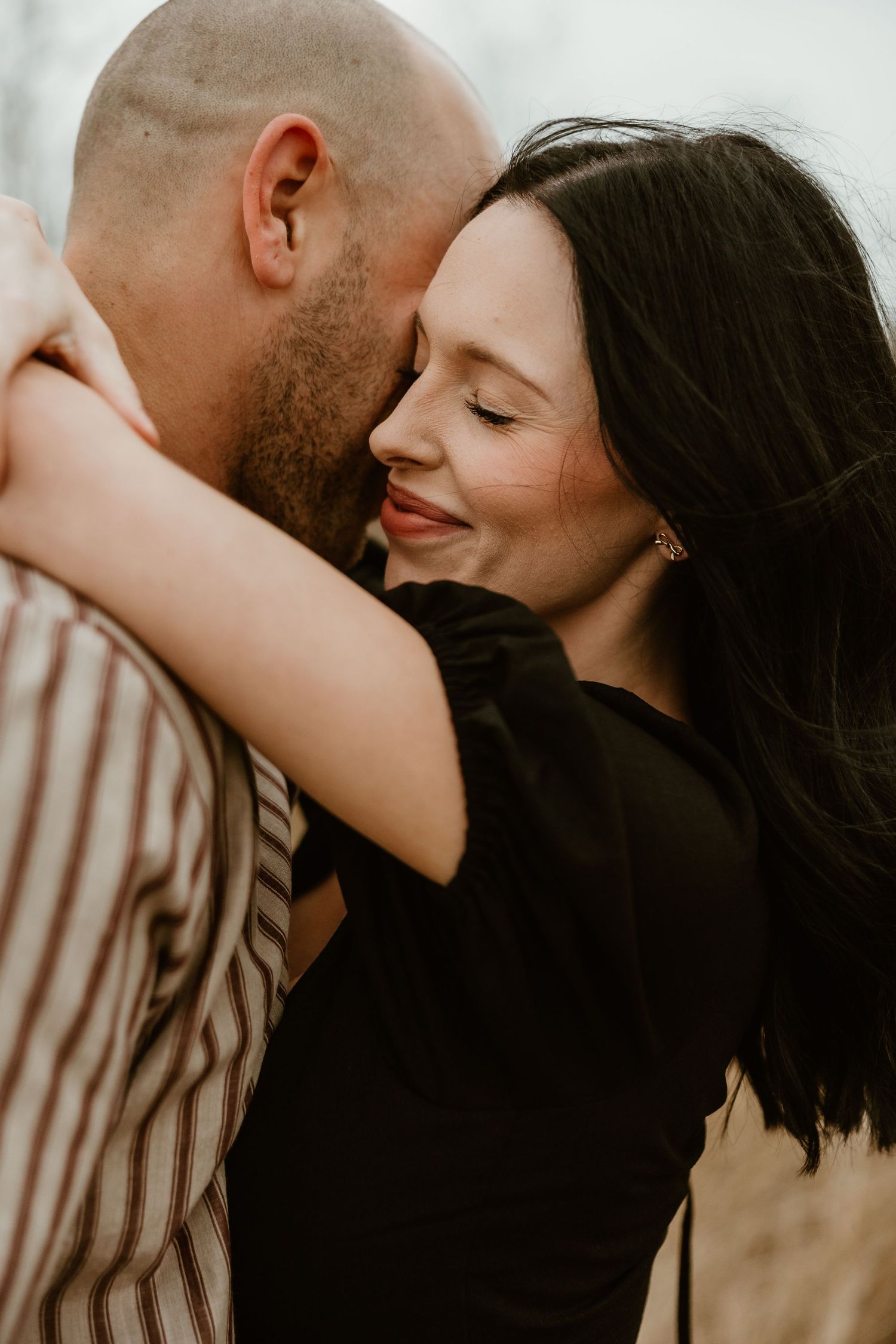 An intimate couple embraces in warm sunlight while sharing a tender moment together.