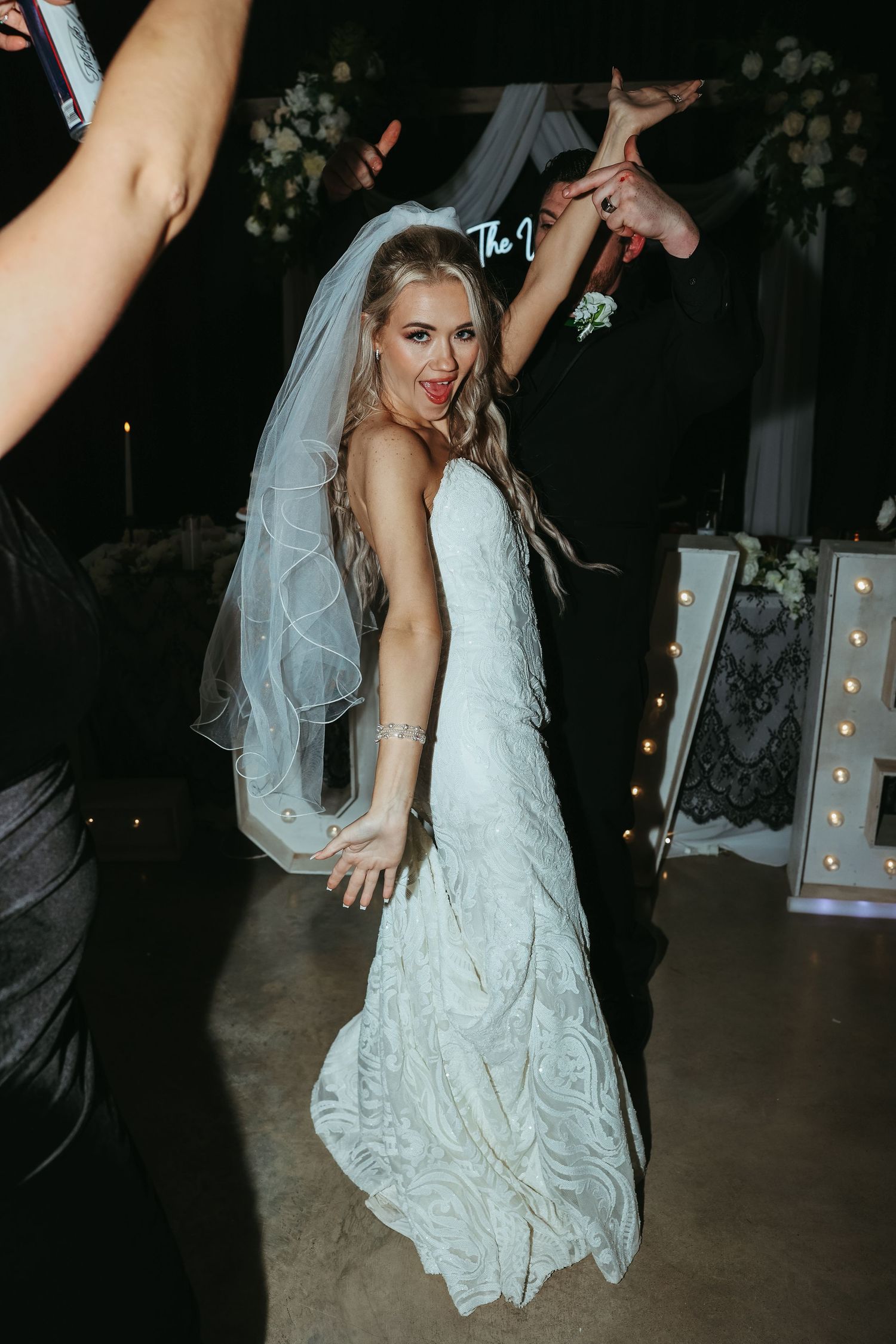 A bride dancing in a fitted lace wedding dress and veil during the reception at a dark, intimate venue.