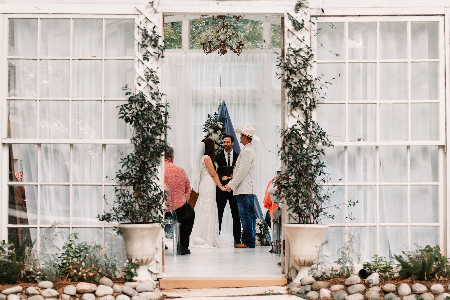 A couple shares a romantic moment under a floral arch at an intimate outdoor wedding ceremony.