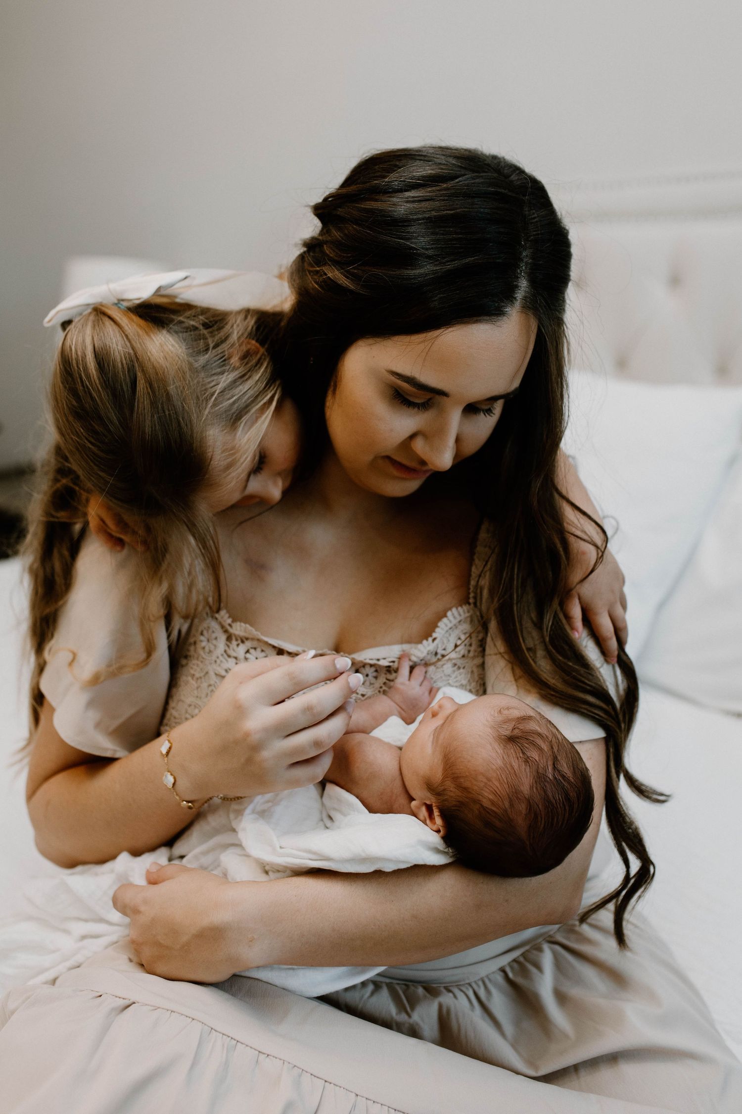 A tender moment as a parent feeds a newborn baby while sitting on a bed.