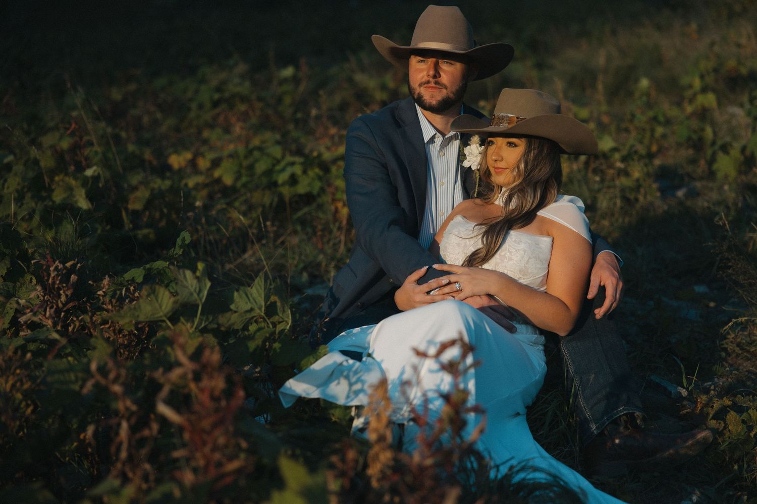 A romantic moment captured in a rustic outdoor setting with natural greenery.