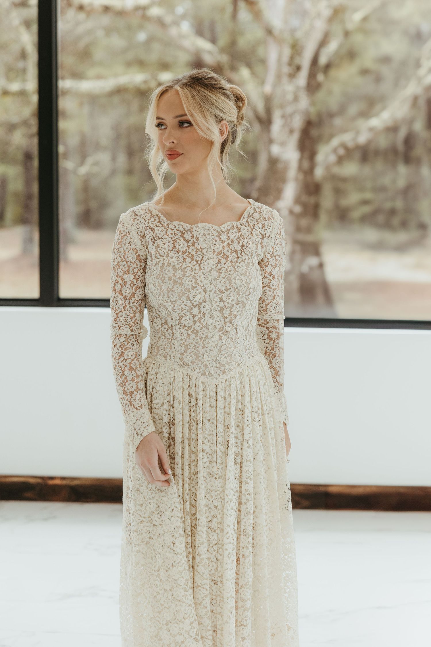 Elegant long-sleeved lace wedding dress in ivory features delicate floral patterns and a flowing A-line silhouette.