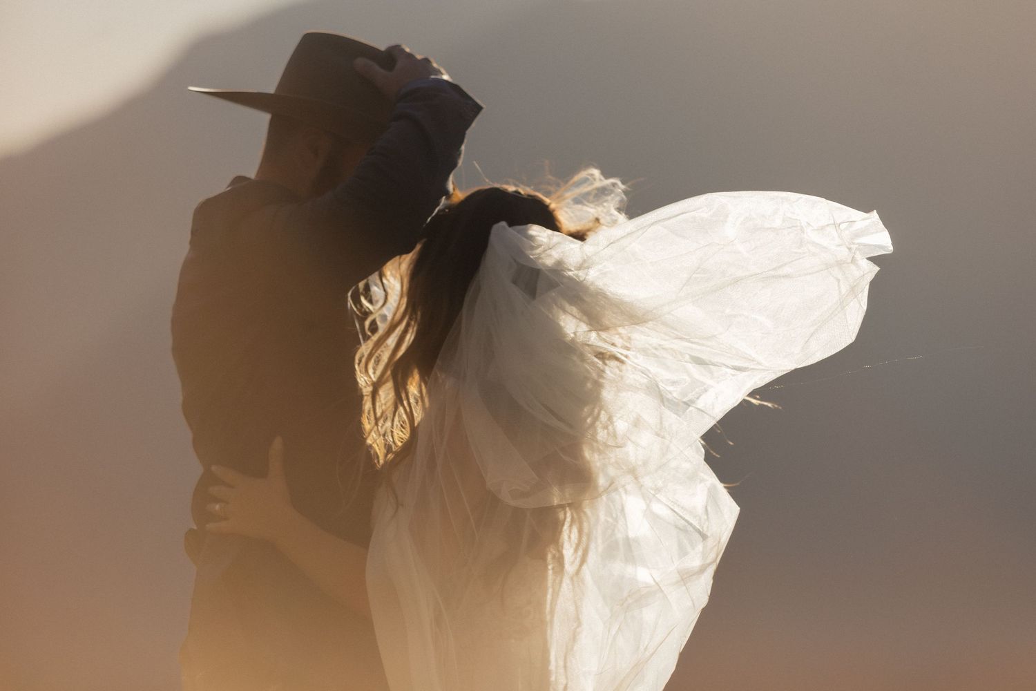 Silhouetted figures against a bright background with flowing white fabric creating an ethereal effect.