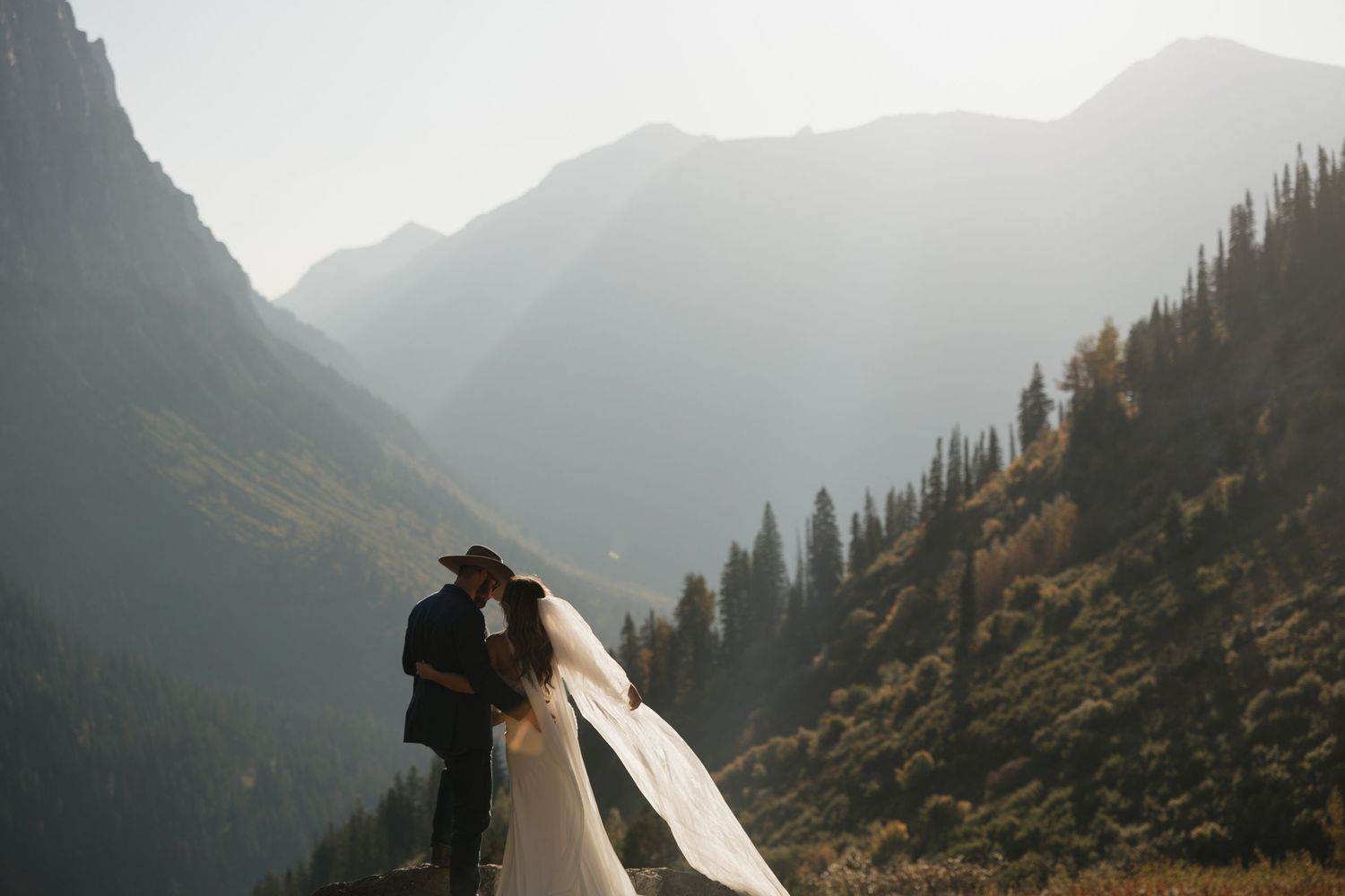 Dramatic mountain vista with layered peaks silhouetted against a misty sky during golden hour.