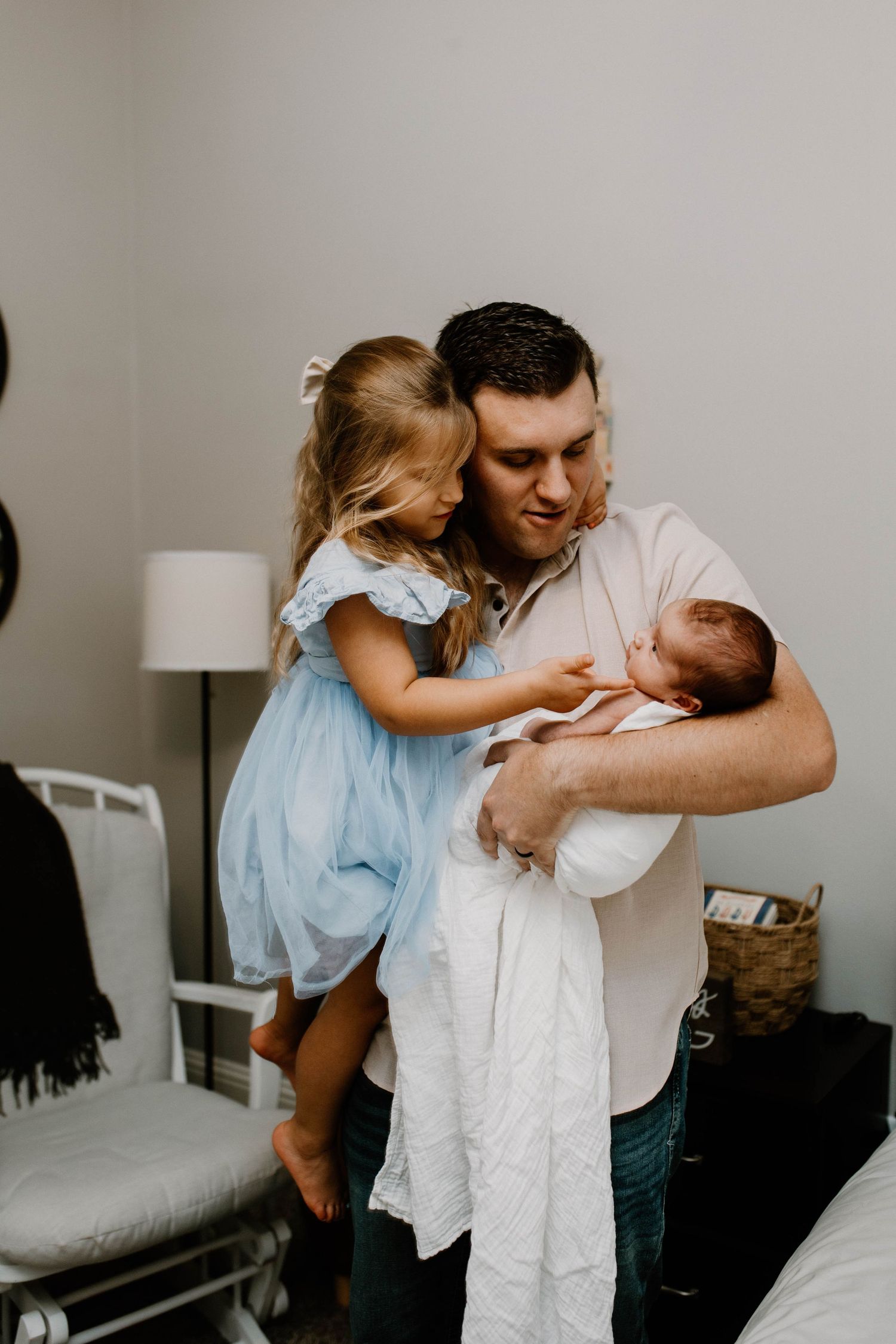 A heartwarming family moment as siblings meet their new baby indoors.