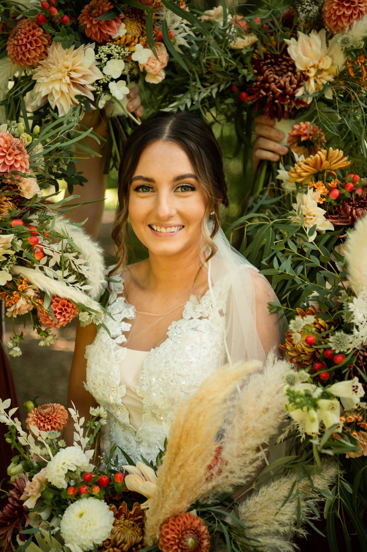 Beautiful floral frame of autumn flowers surrounds elegant bridal portrait.