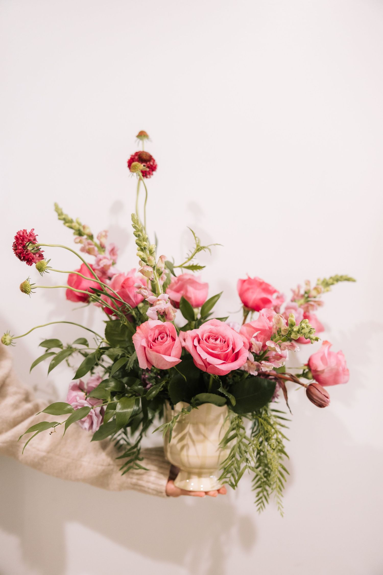 A series of pink rose floral arrangements with greenery displayed on a white surface in varying compositions.
