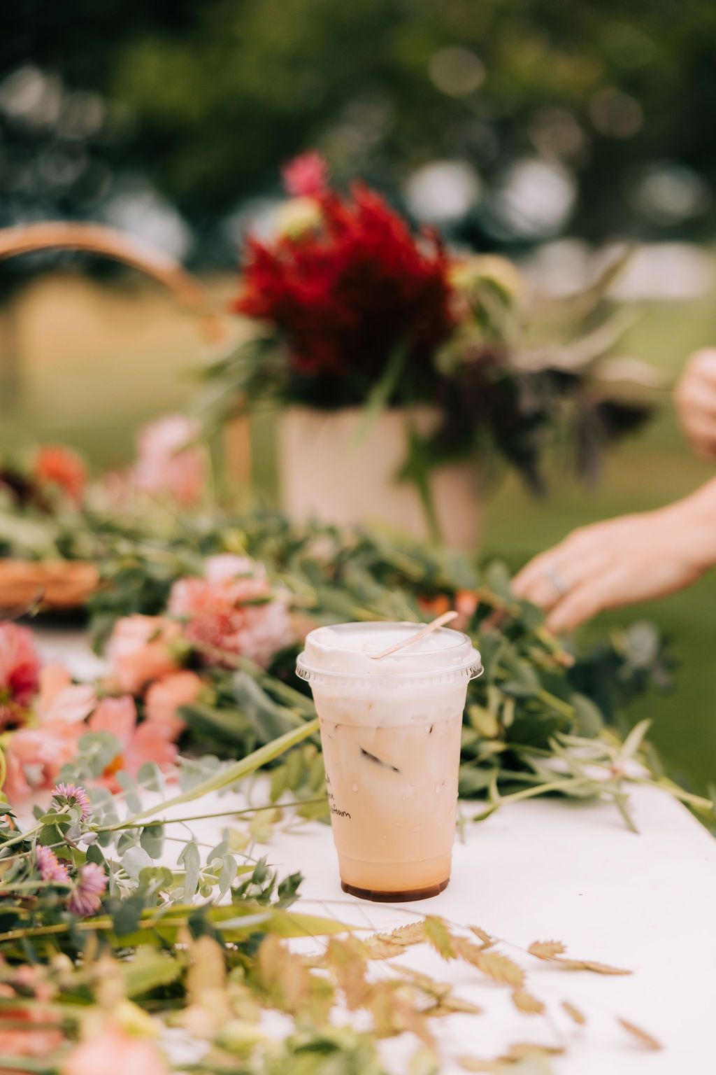 White candles and delicate floral arrangements create an elegant outdoor table setting with soft pink and green accents.