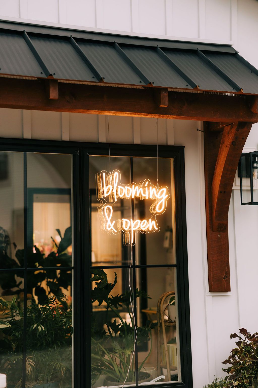 Illuminated neon sign reading 'Morning & open' glows through a storefront window beneath a green metal awning.