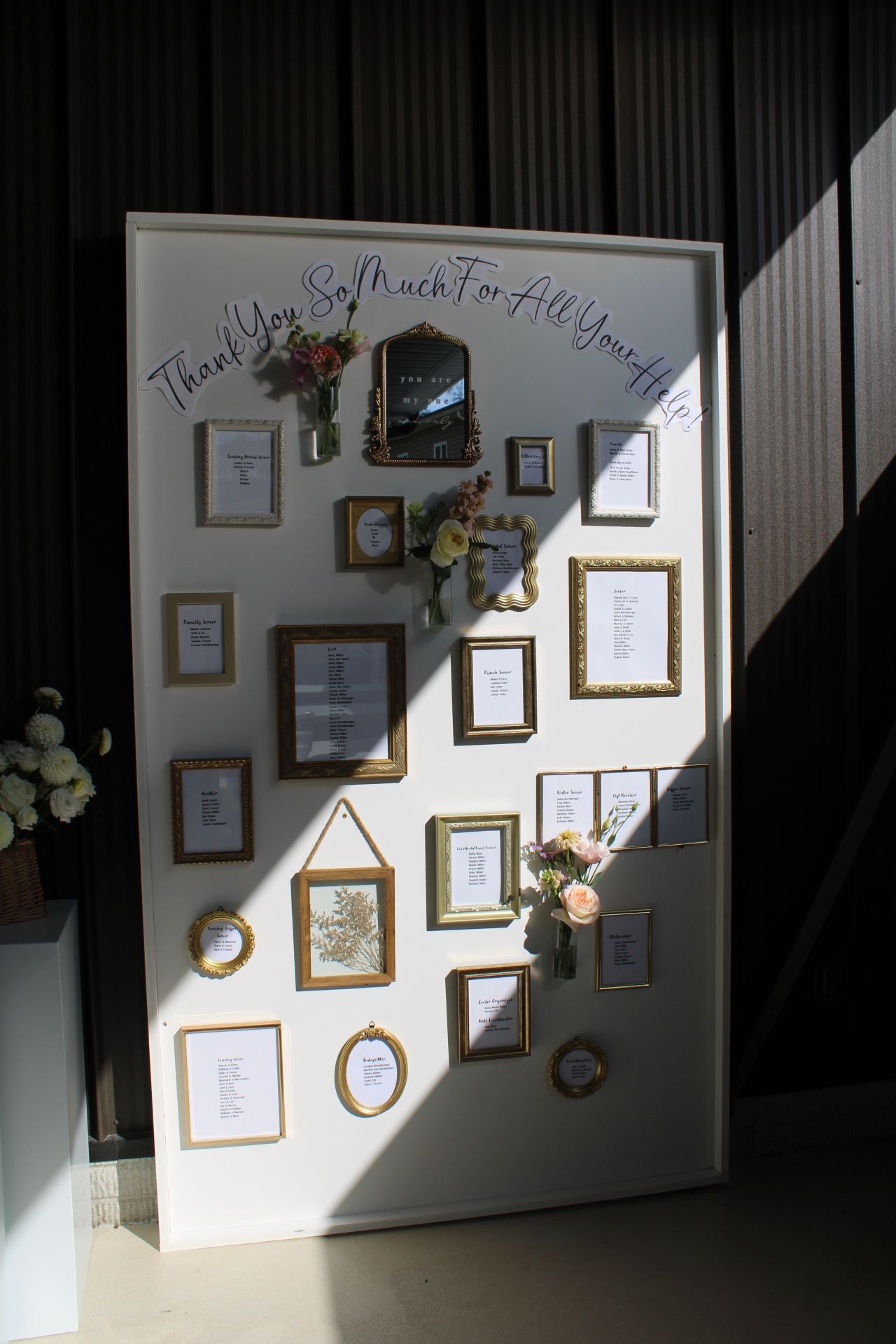 A gallery wall display with framed artwork and decorative elements arranged in a pattern on a white wall.