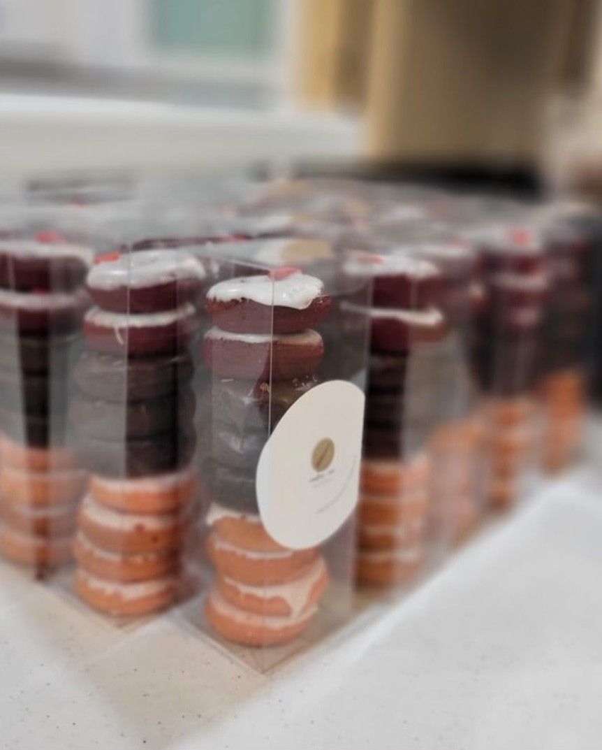 Glass jars filled with pink sauce arranged in neat rows on a white surface.