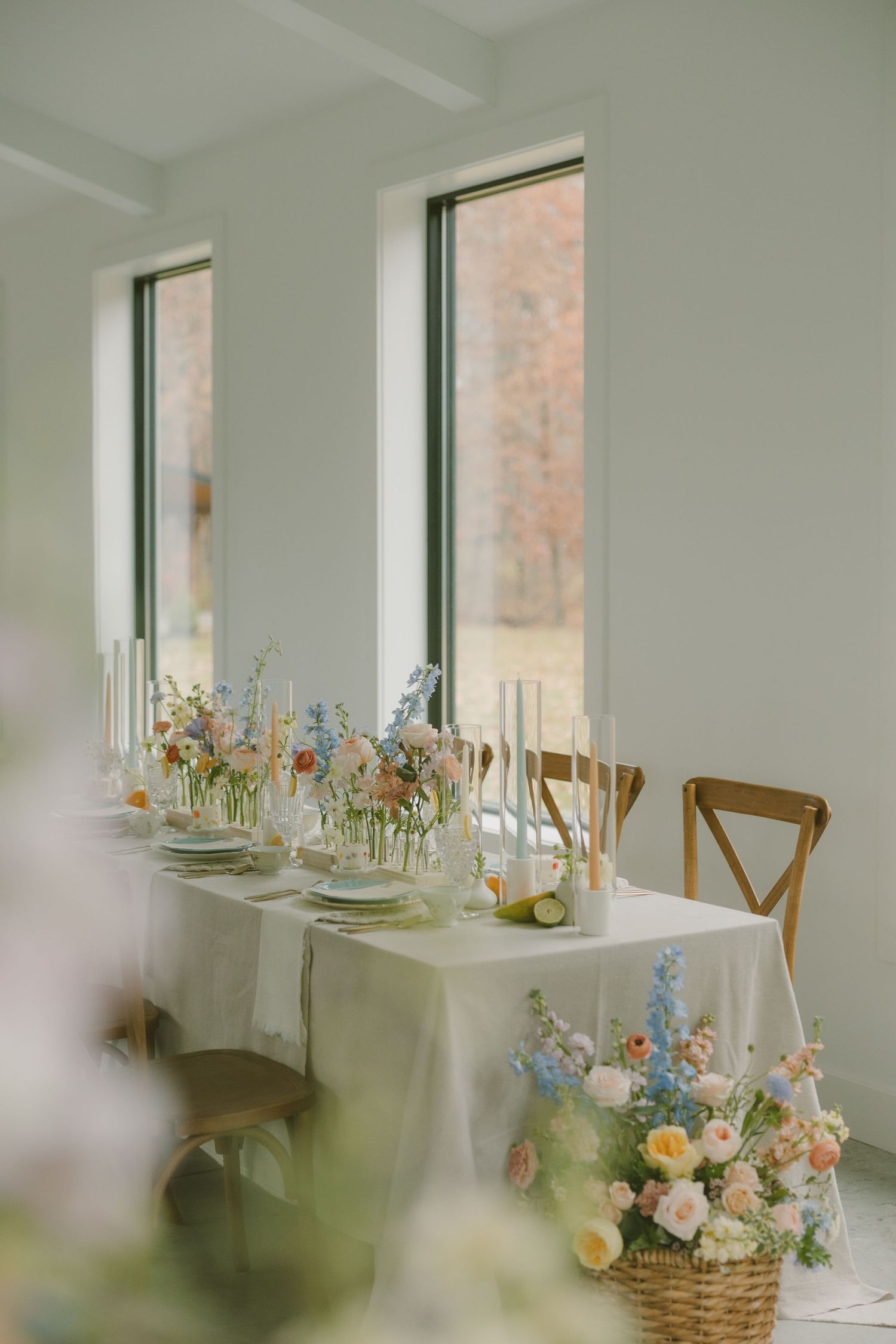 An elegant wedding table setting with delicate floral centerpieces and candlesticks near tall windows.