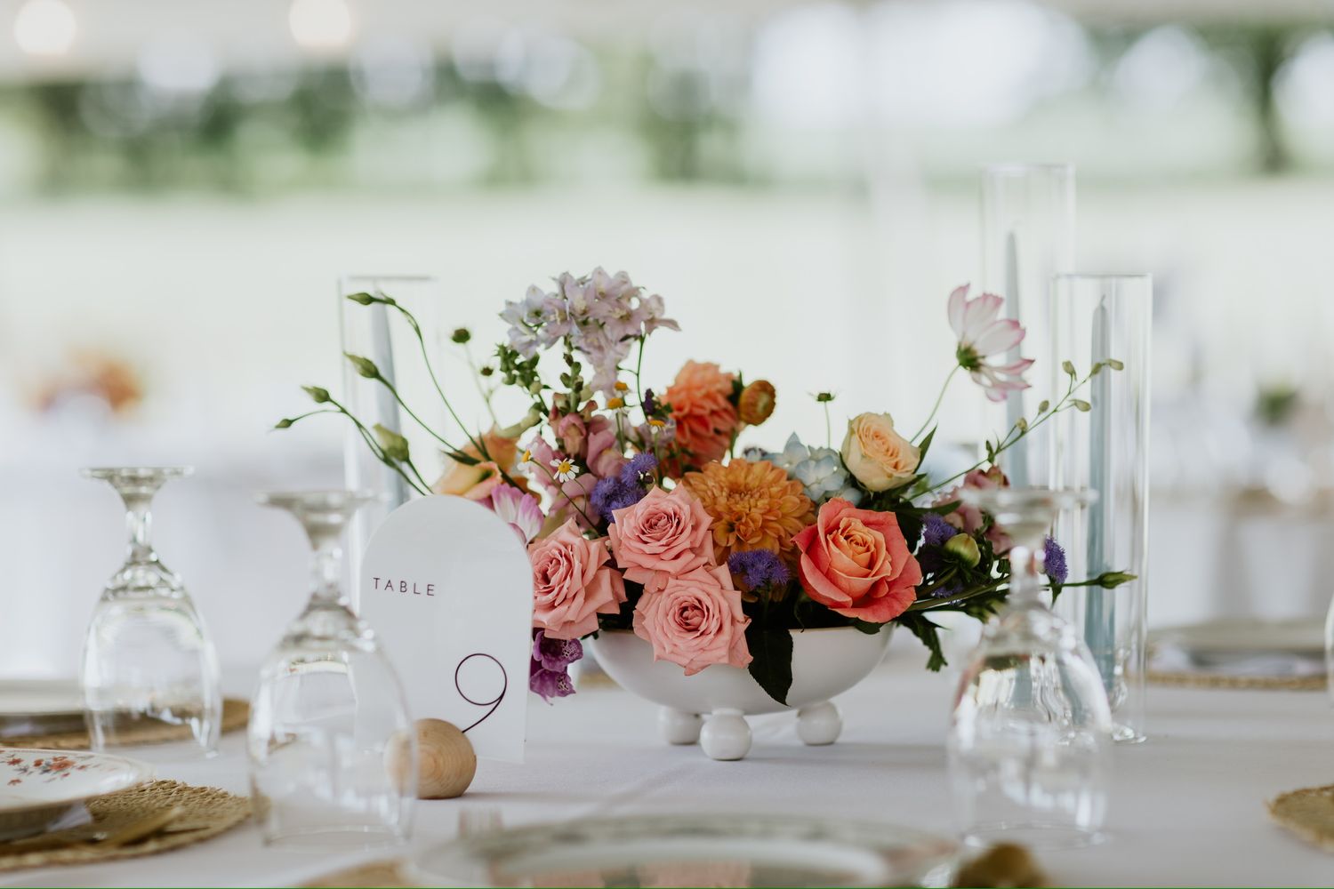 Romantic coral and pink floral centerpiece with rustic table decor at wedding reception.