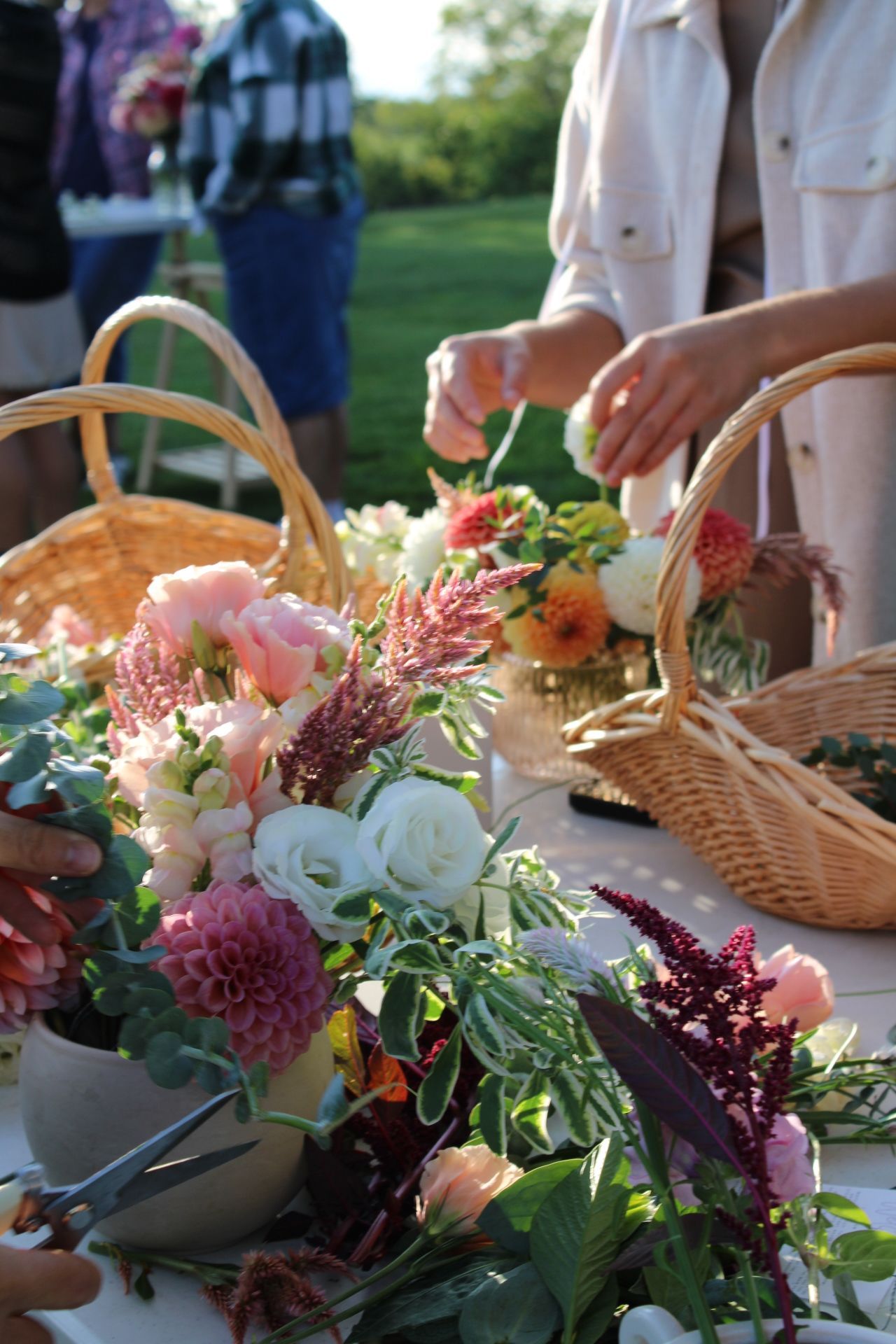 Close-up of flower arrangement being created with pink and white blooms in wicker baskets.