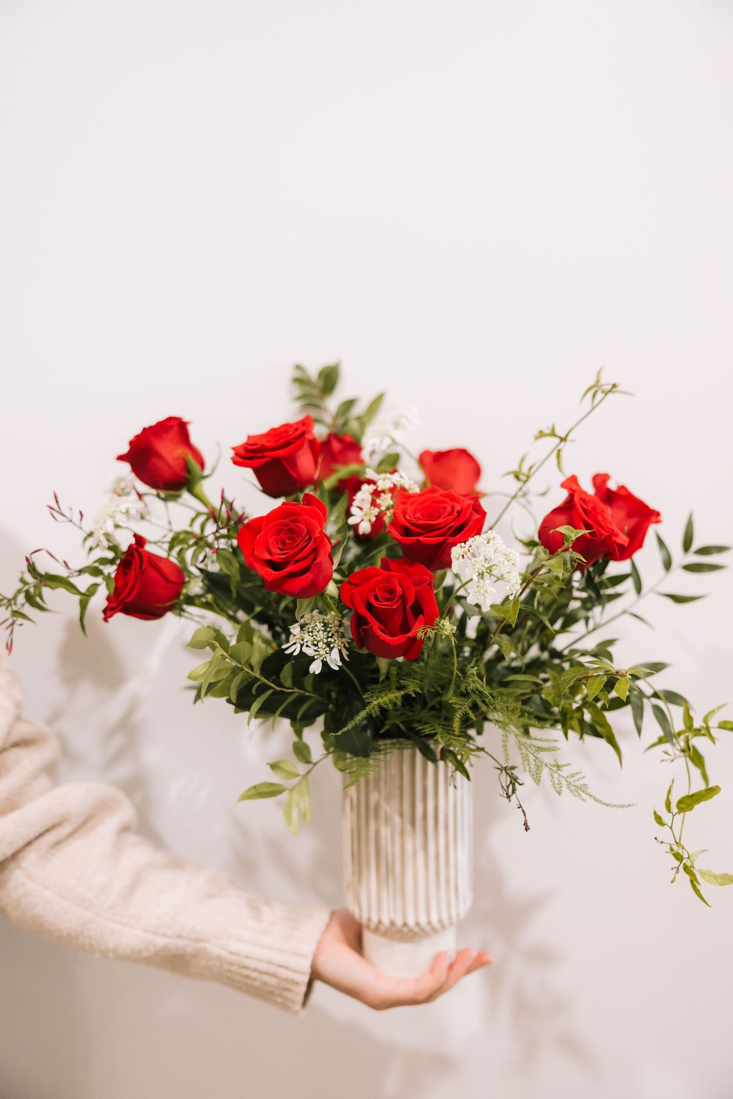 A series of four photos showing red roses and white flowers arranged in a ribbed vase against a light background.