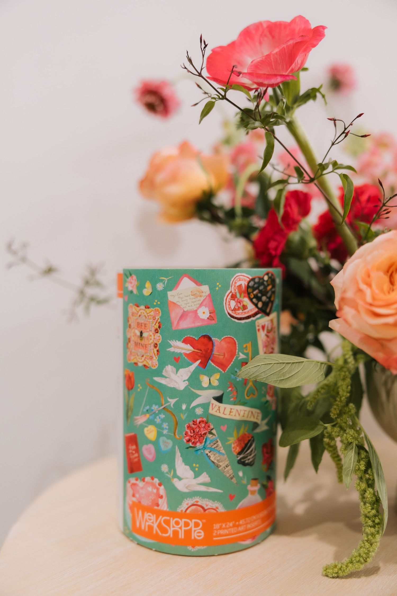 Decorative turquoise tin canisters with whimsical animal designs displayed alongside pink and peach roses and greenery.