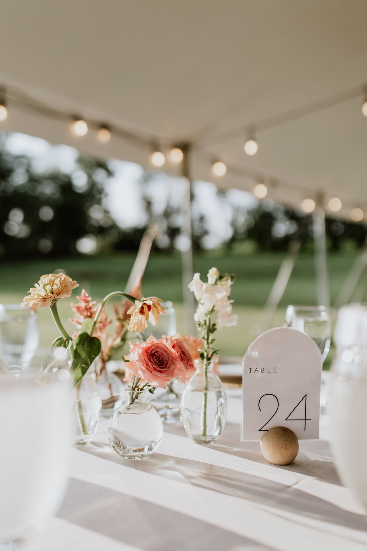 Wedding table setting with delicate floral arrangements and table number 24 under string lights.