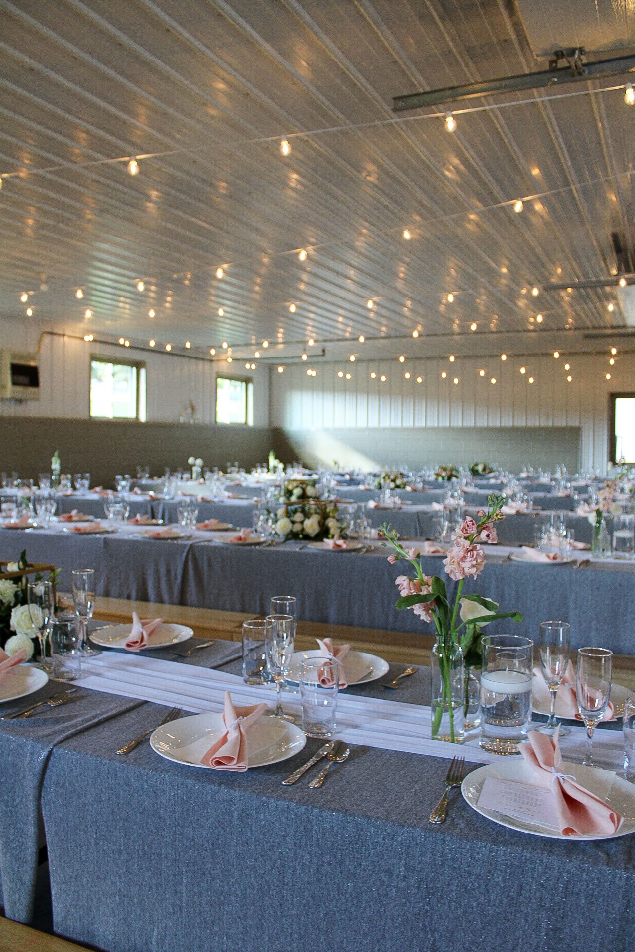Large wedding reception hall with blue tablecloths and string lights creating an elegant atmosphere.