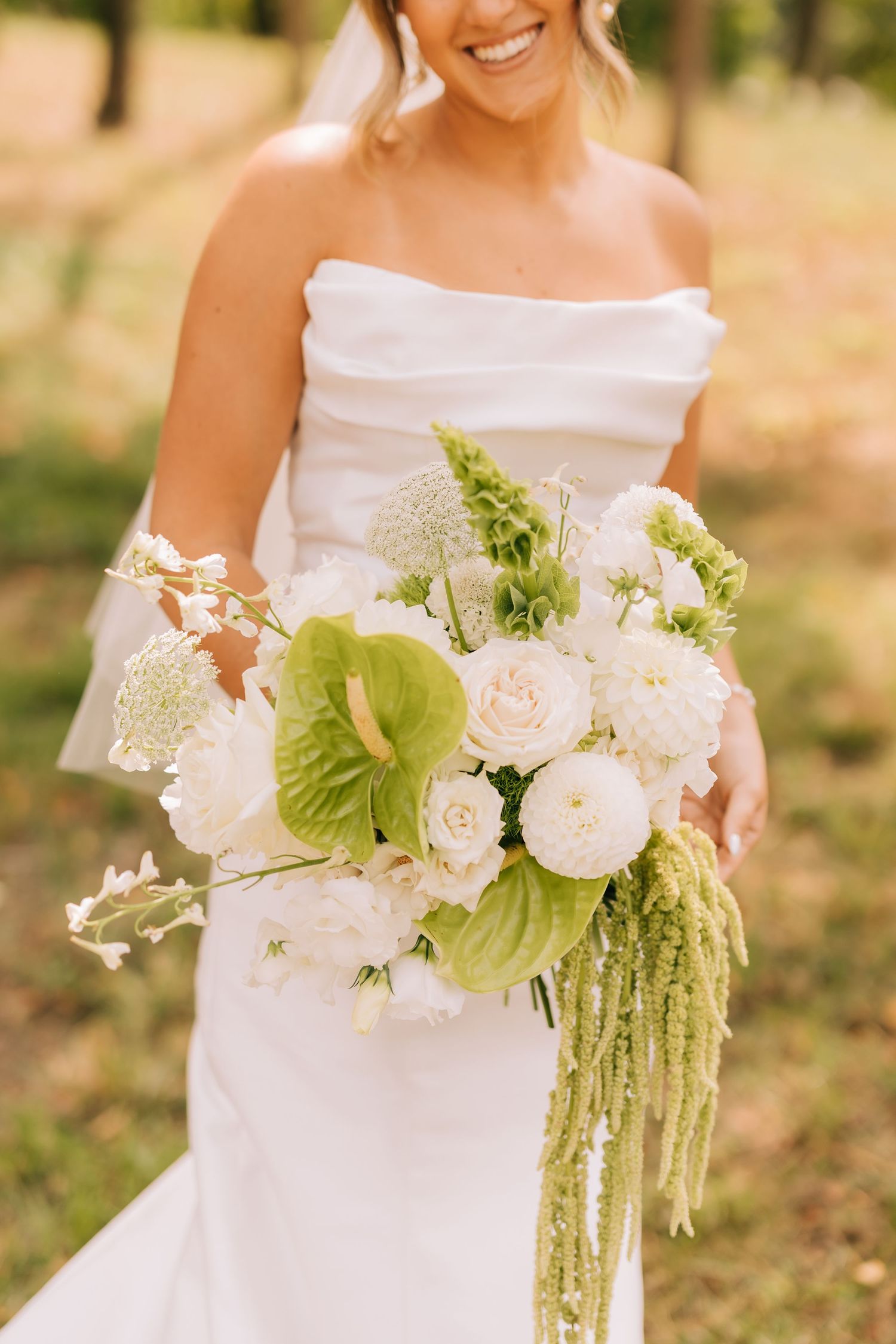 A beautiful cascading bridal bouquet with white roses, green amaranthus, and delicate Queen Anne's lace flowers.