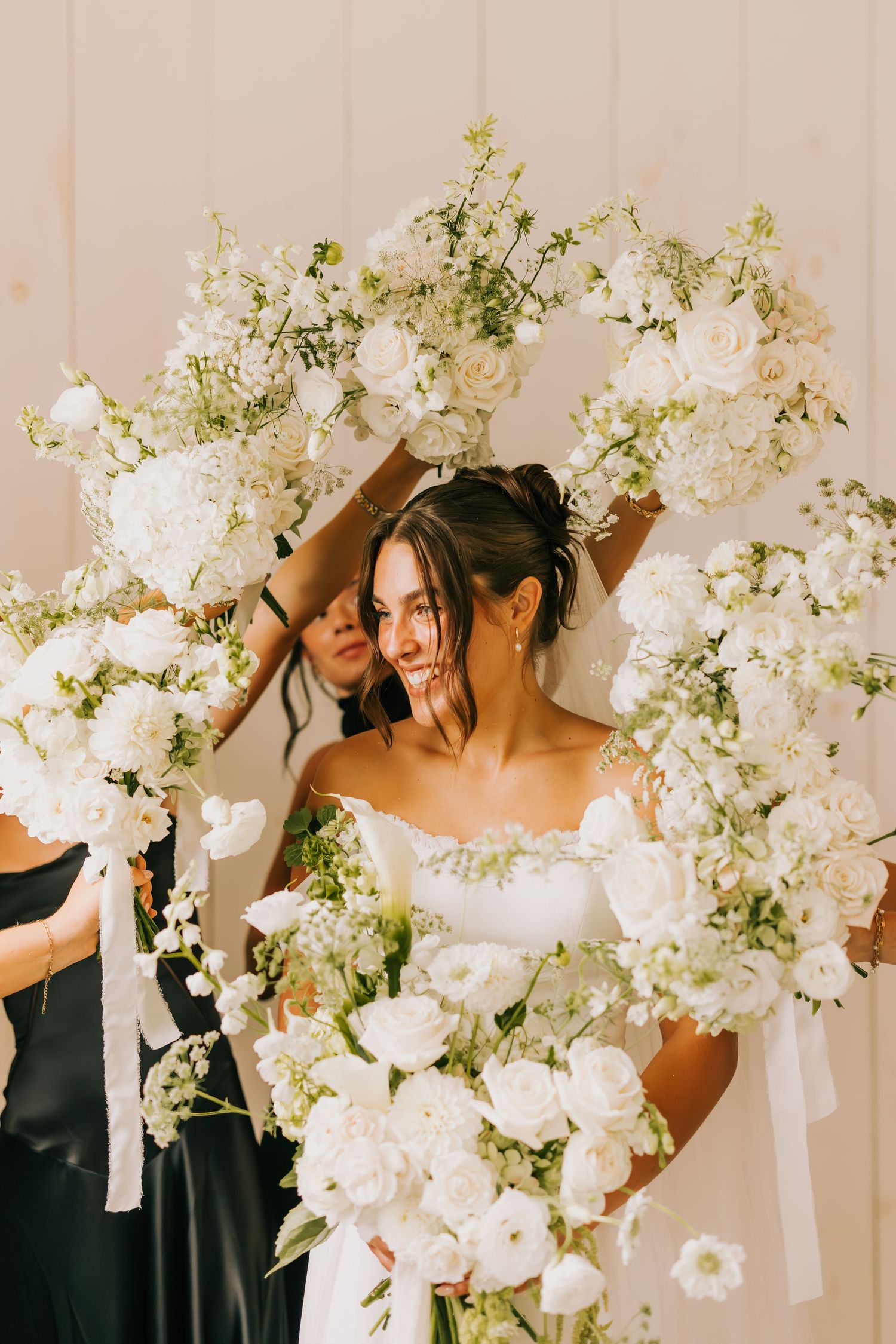 Elegant white floral arrangements with roses and delicate blooms cascade against a light backdrop at a wedding celebration.