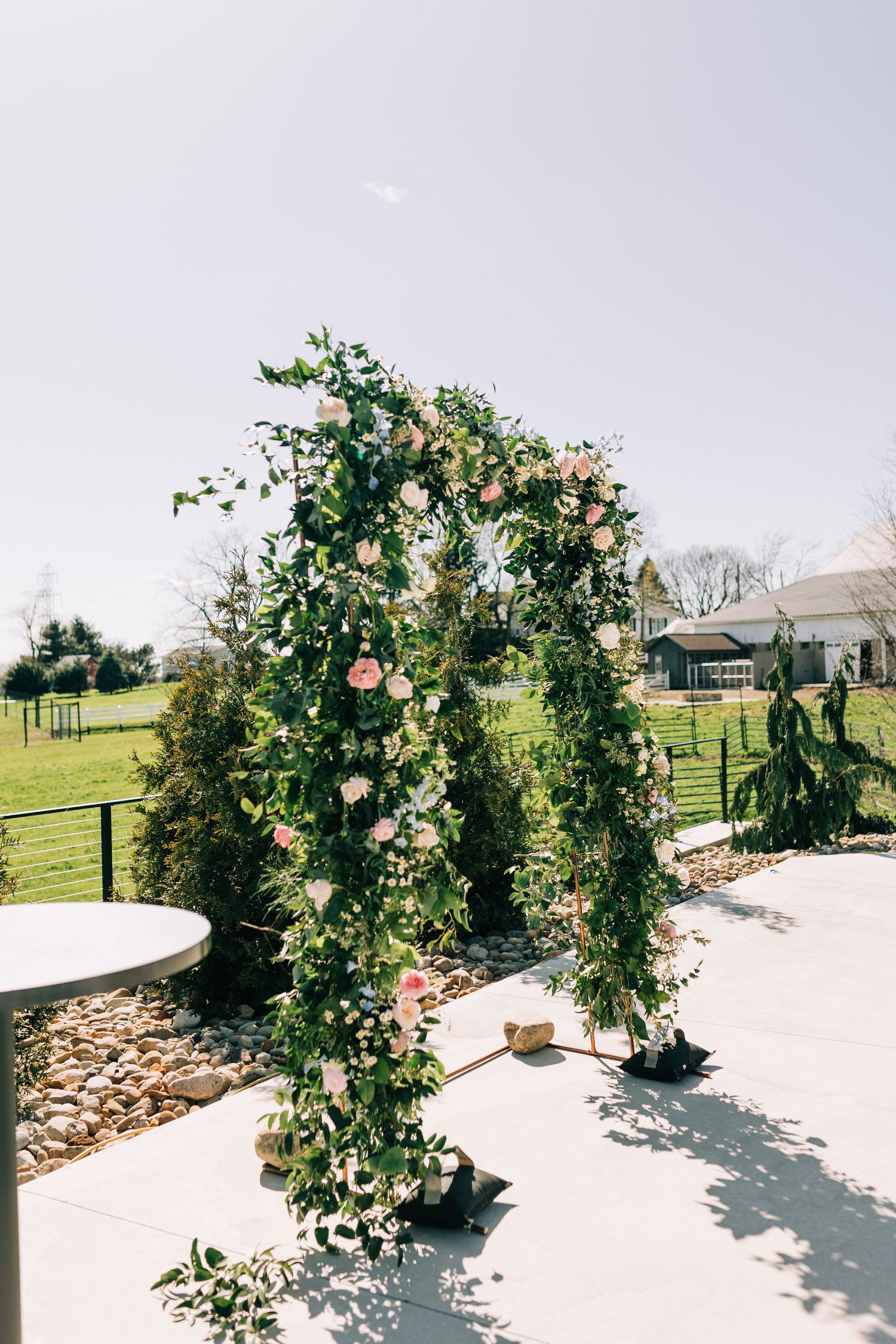 A romantic floral arch with pink roses and greenery creates an enchanting wedding ceremony backdrop.