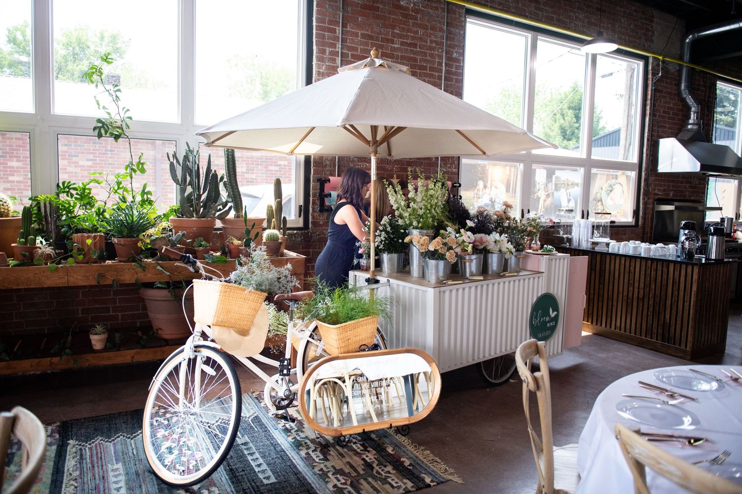 Decorative vintage bicycle with umbrella and flowers displayed at indoor venue setup.