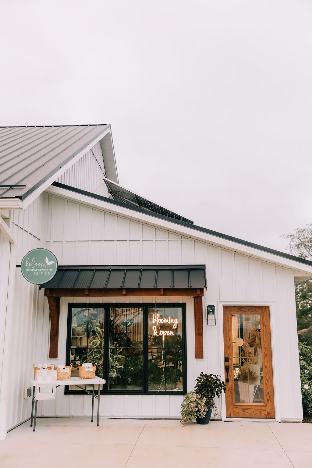 Modern white farmhouse exterior with black trim windows and wooden door showcases clean architectural lines.