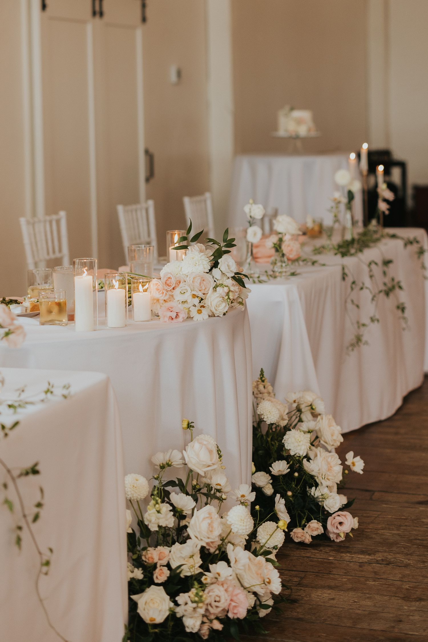 Elegant white reception table with blush roses and candles cascading down the sides.