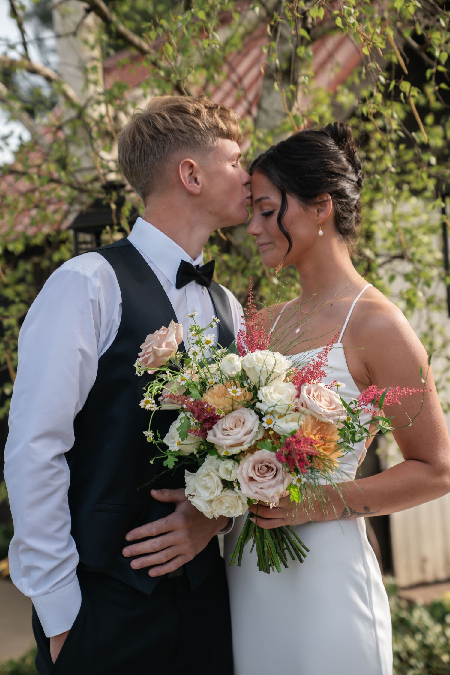 Romantic outdoor wedding portrait with soft peach and white floral bouquet.