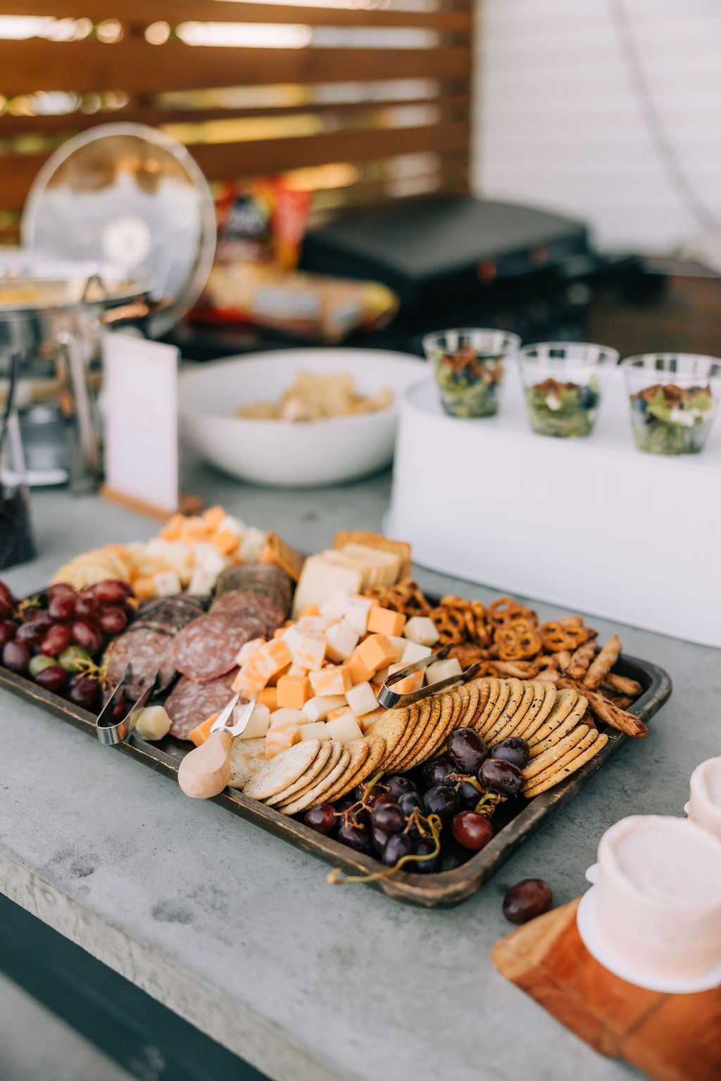 Elegant charcuterie board displays assorted cheeses, crackers, grapes, and nuts arranged on stone serving platters.