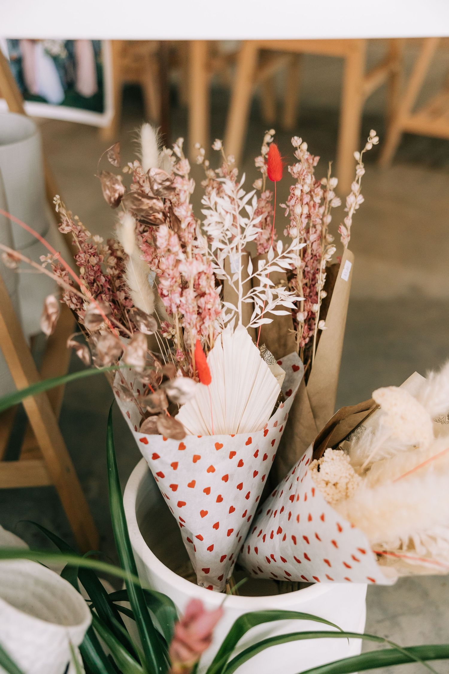 Dried floral bouquets wrapped in polka dot paper displayed in white ceramic container.