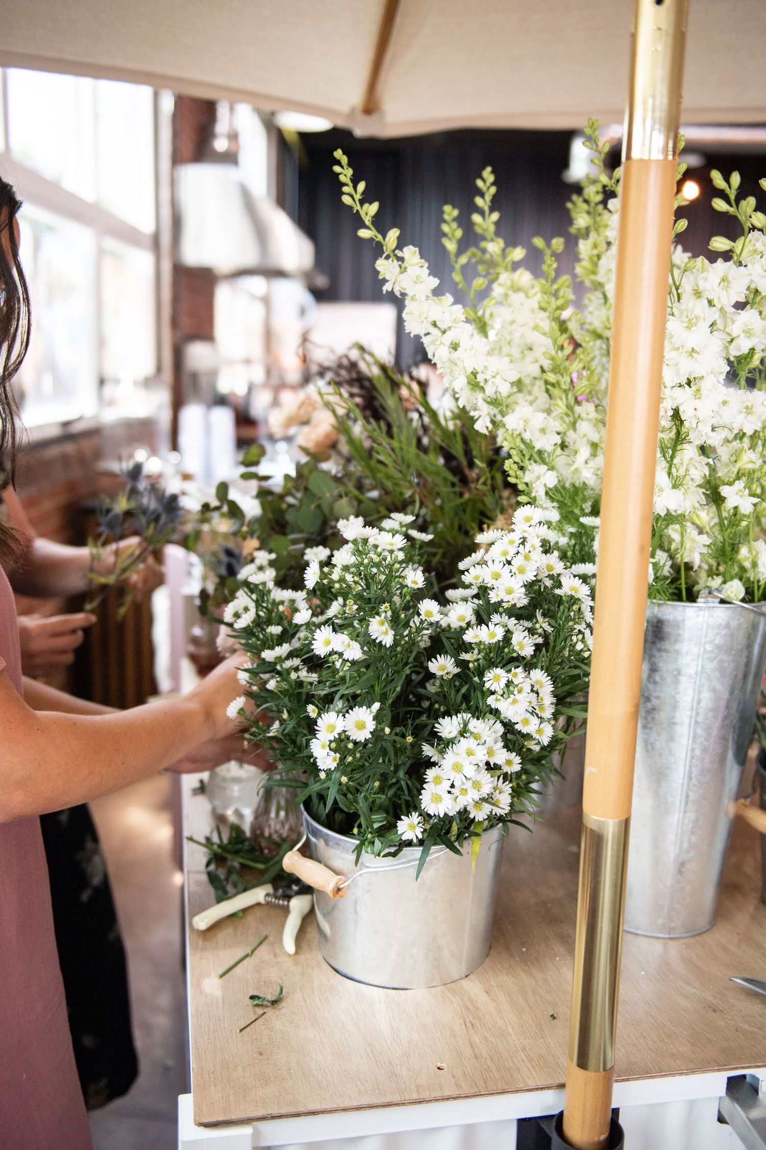 White delicate flowers arranged in a galvanized metal bucket on a wooden surface.