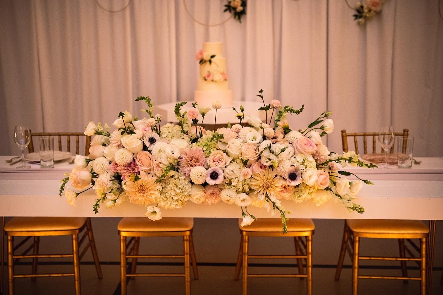 Luxurious floral centerpiece with white and blush flowers adorning an elegant head table.