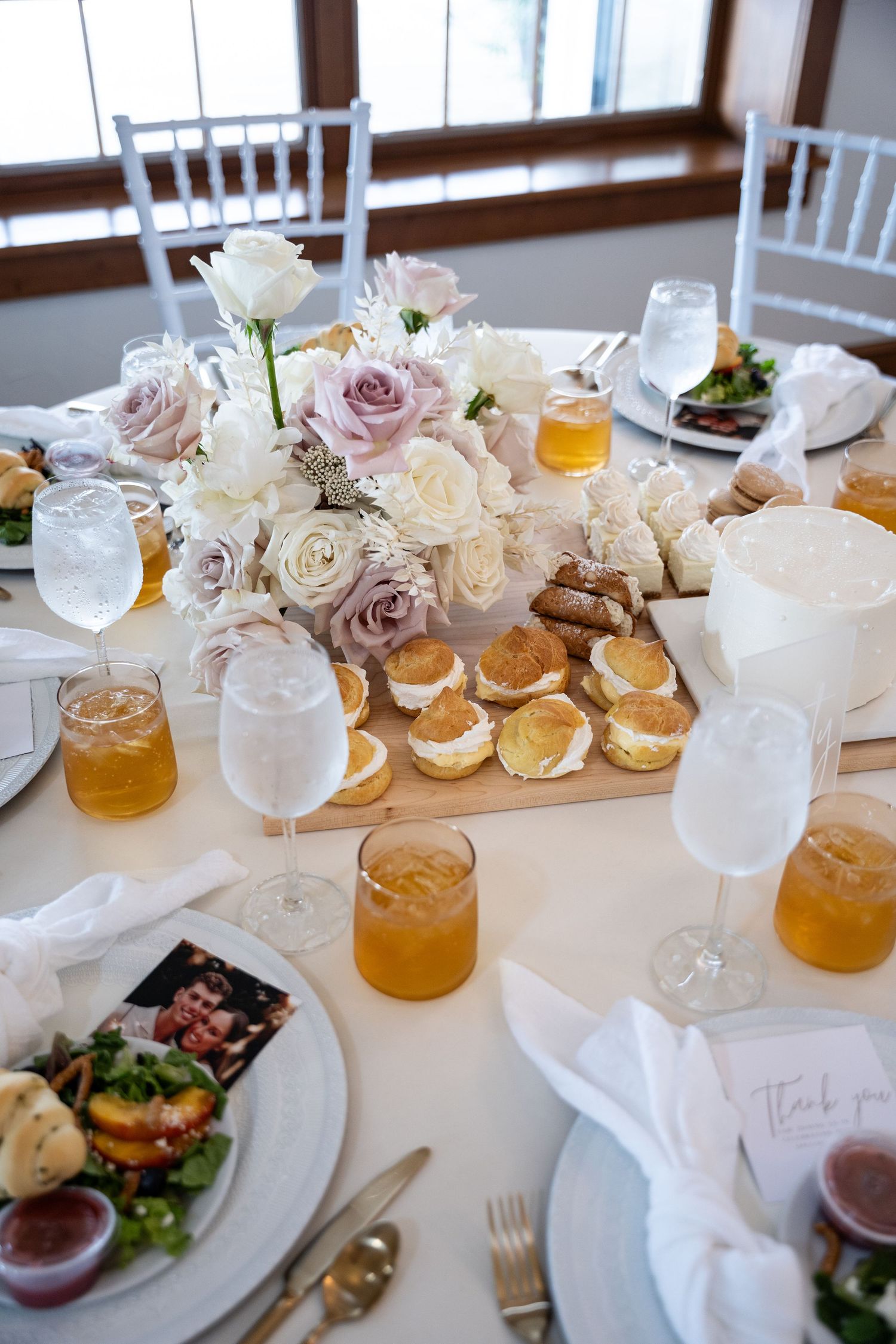 Wedding table setting with pink and white roses, appetizers, and honey-colored drinks in glasses.