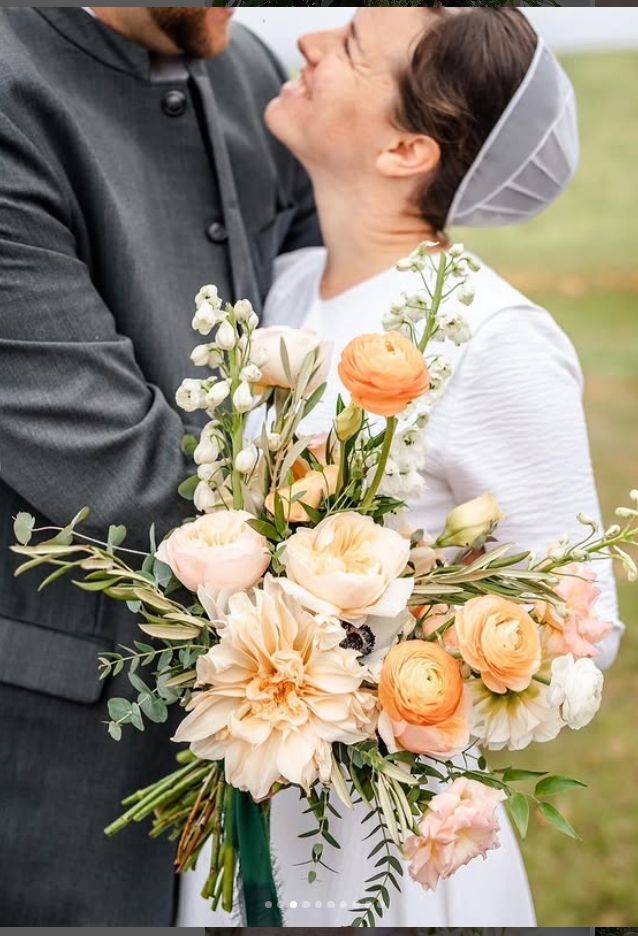 Closeup of peach and cream floral wedding bouquet with roses and greenery.
