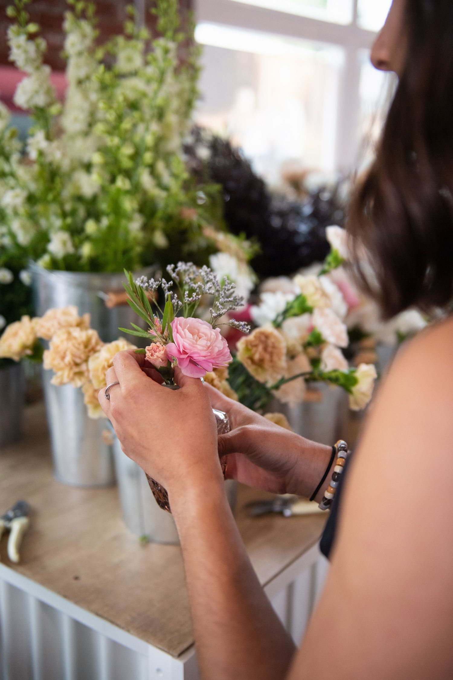 Close-up of hands arranging pink flowers in a floral design workshop.