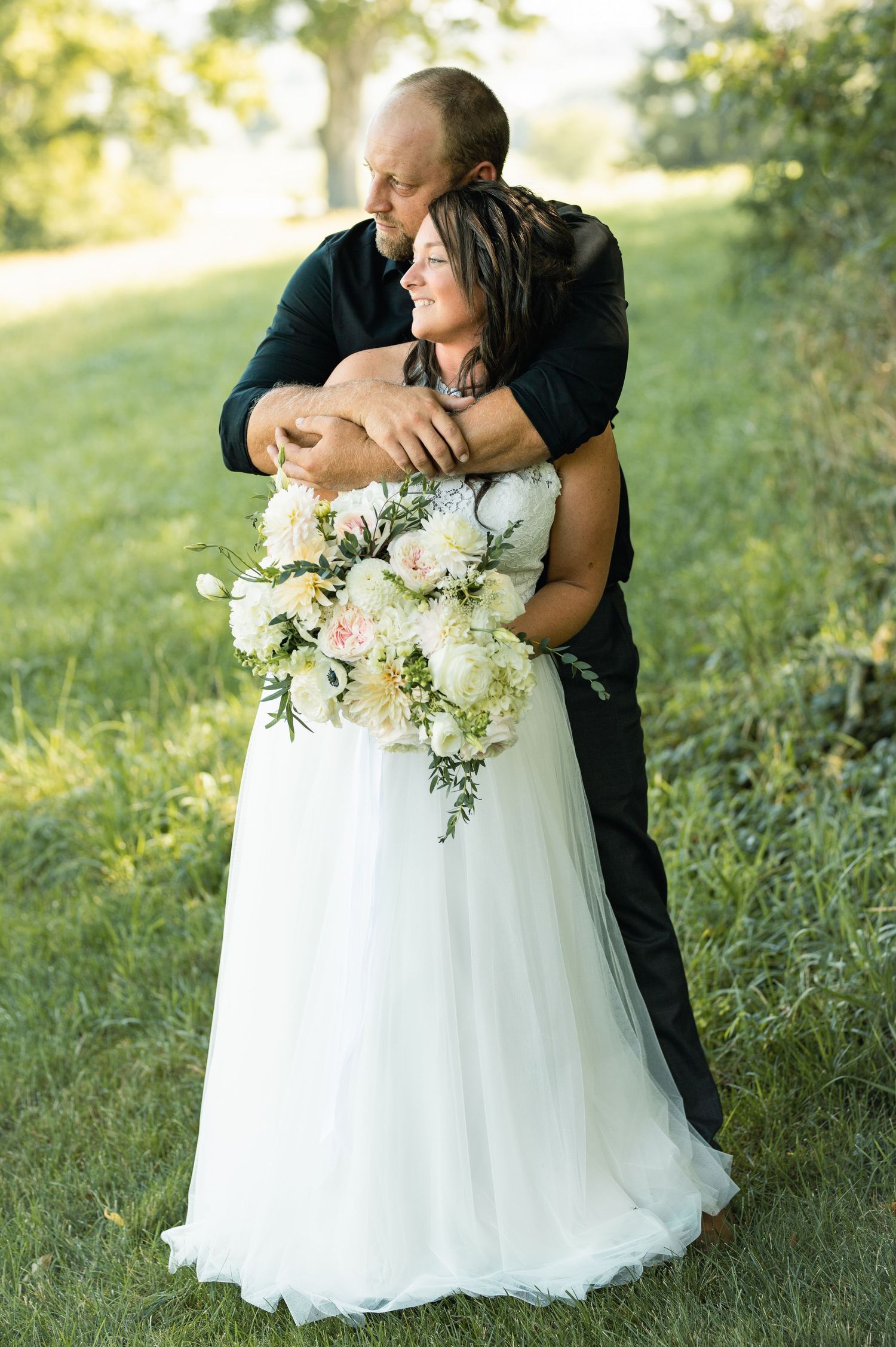 A tender moment captured between a couple in formal attire holding a white floral bouquet.