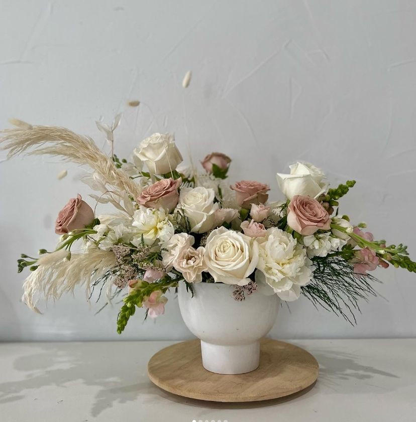 Romantic arrangement of blush and cream roses with pampas grass in modern white vase.