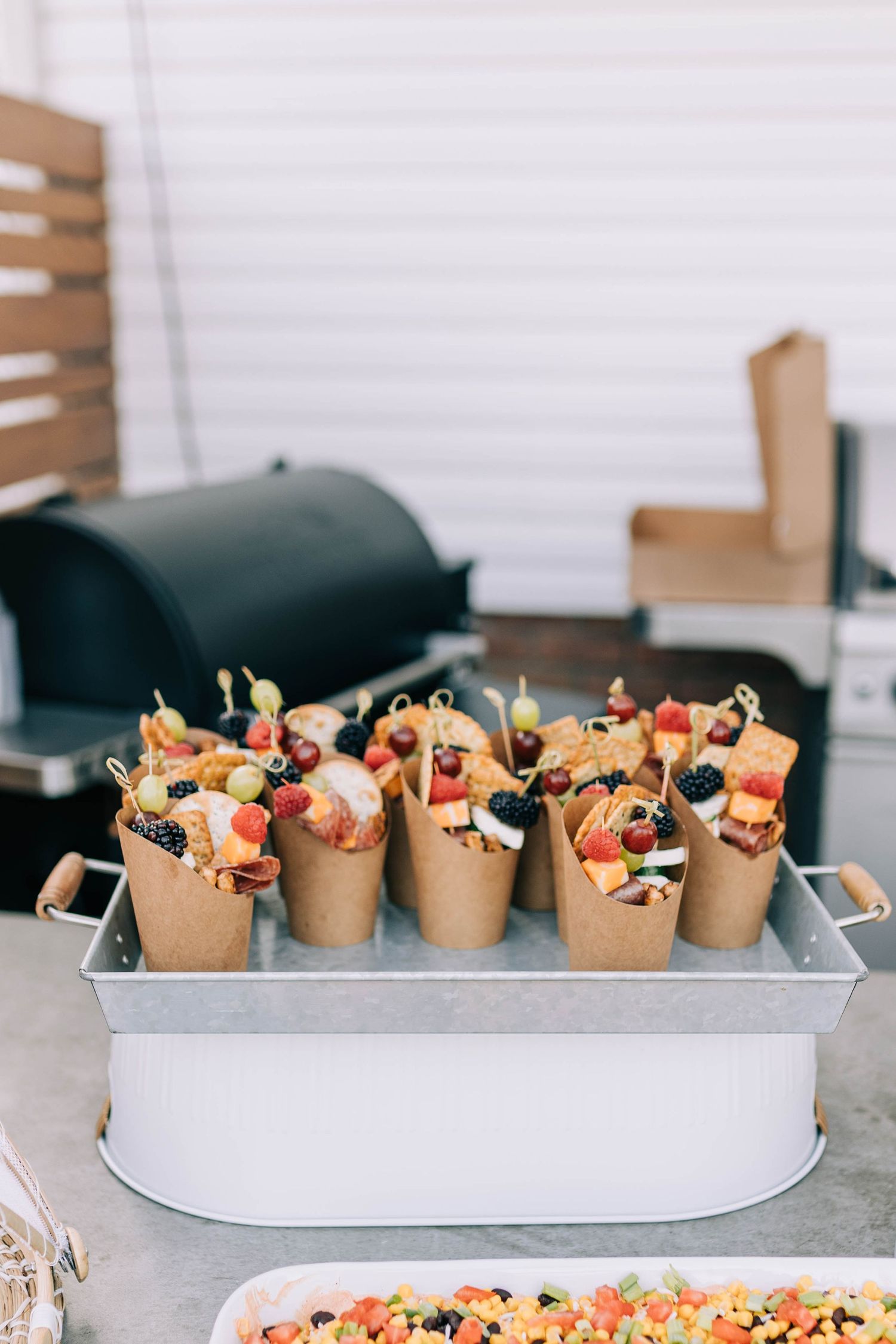 Paper cones filled with appetizers and snacks displayed in metal serving tray.