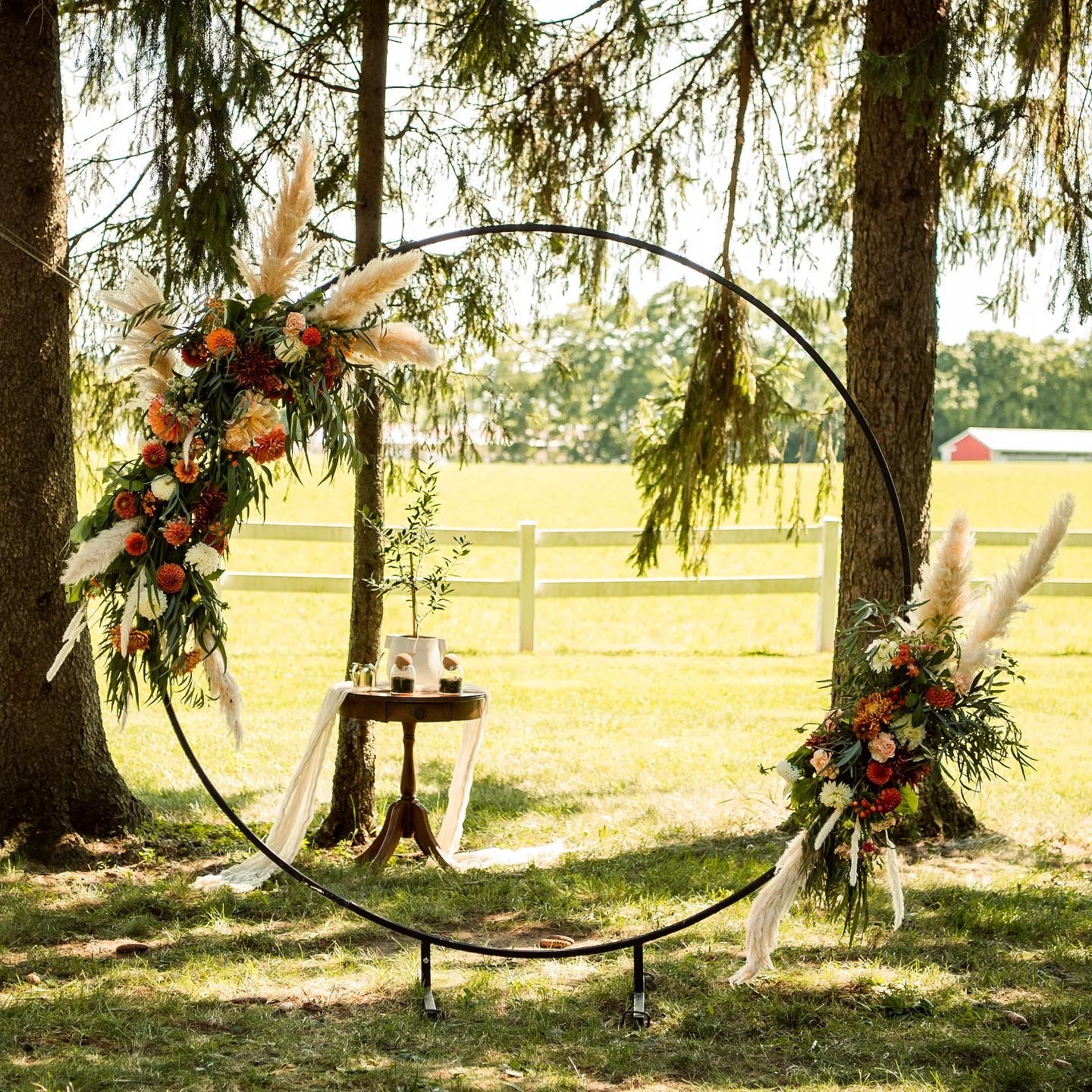 Modern circular wedding arch with asymmetrical floral arrangements in outdoor garden setting.