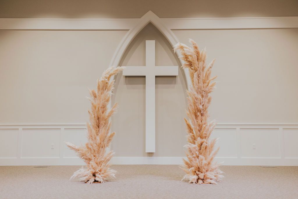 Beige and white dried pampas grass arranged in a modern minimalist vase against a neutral wall.