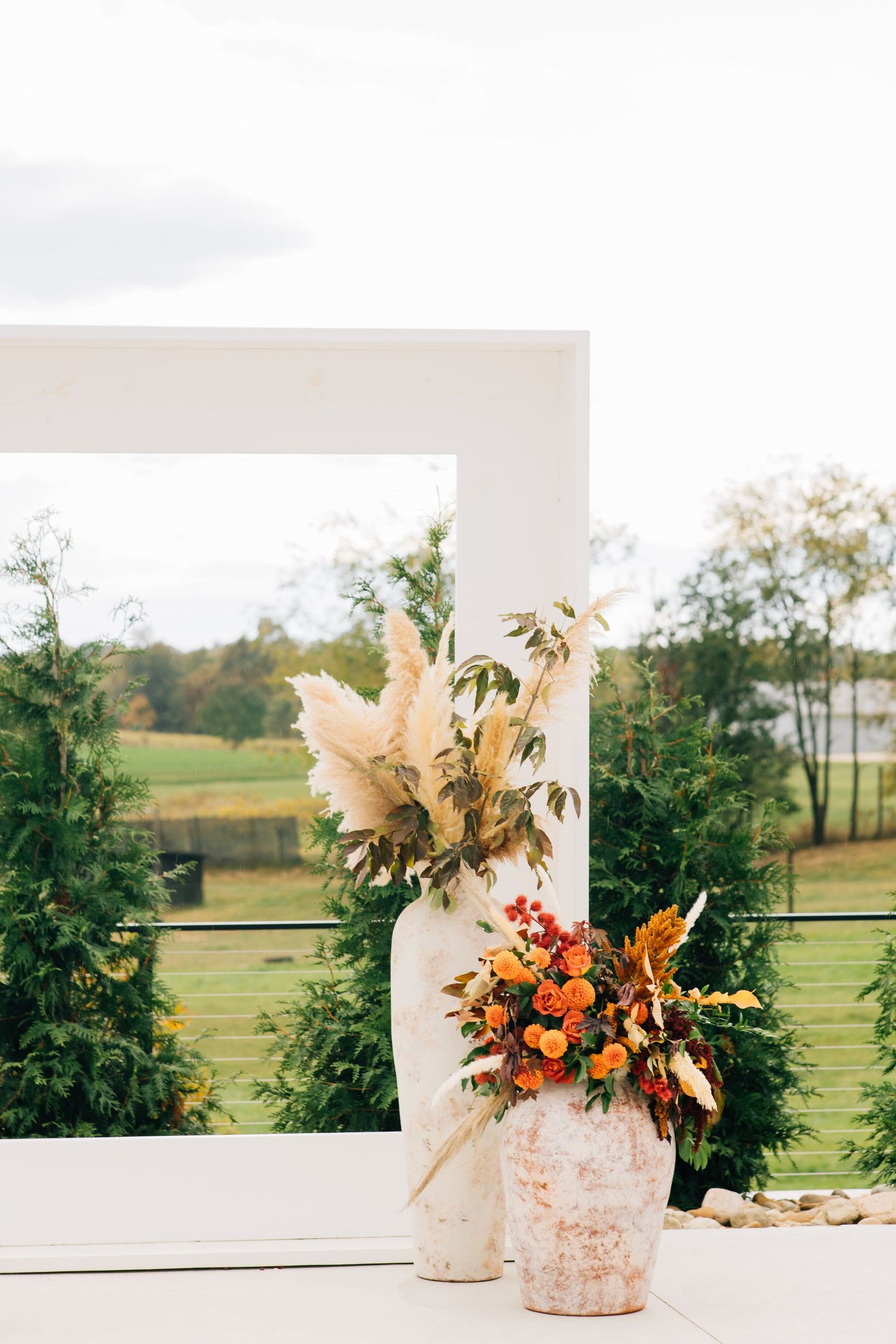 Modern white wedding arch decorated with autumn-colored dried flowers and pampas grass arrangements.