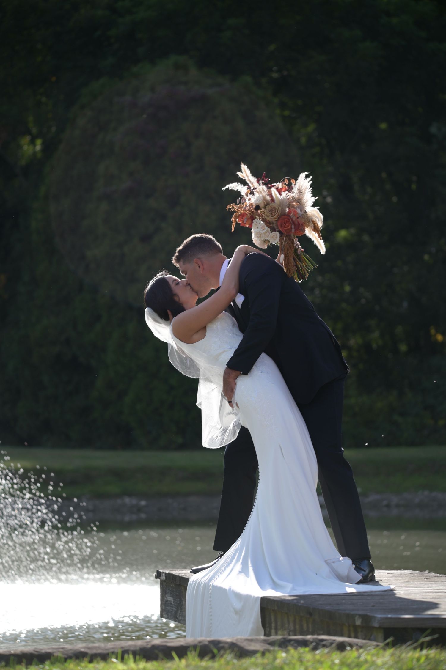 A couple in wedding attire dances and spins by a lake in a romantic sequence of photos.
