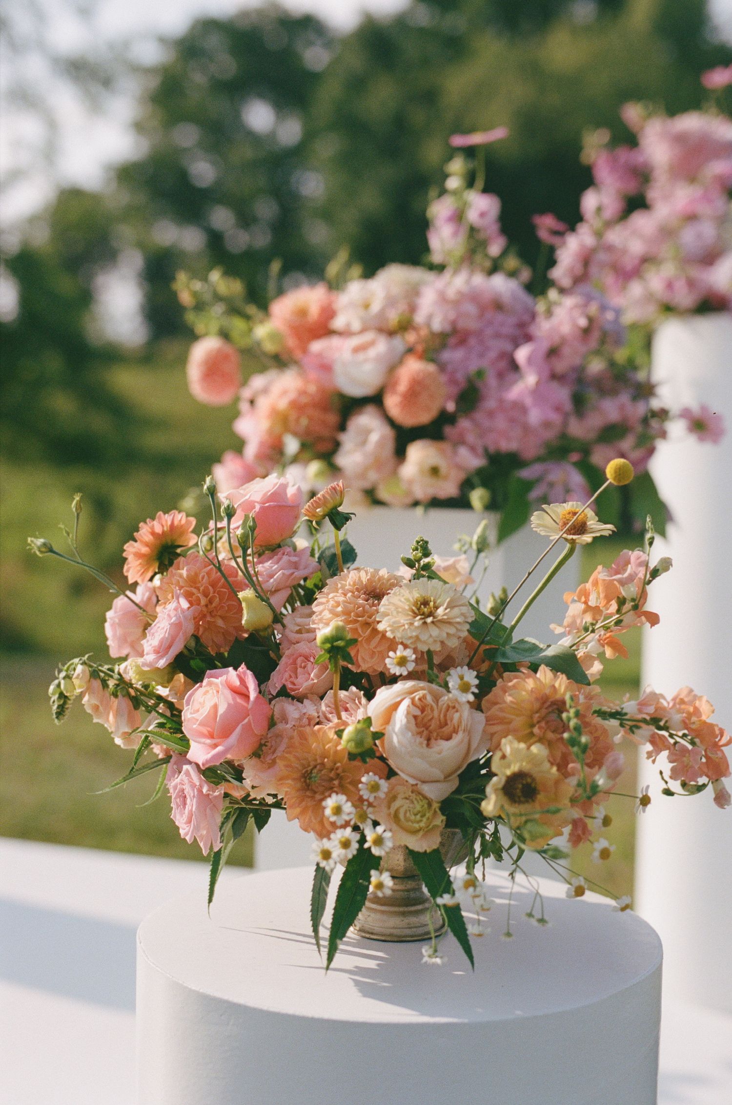 Lush peach and pink floral arrangement in vintage vase with garden roses and delicate blooms.
