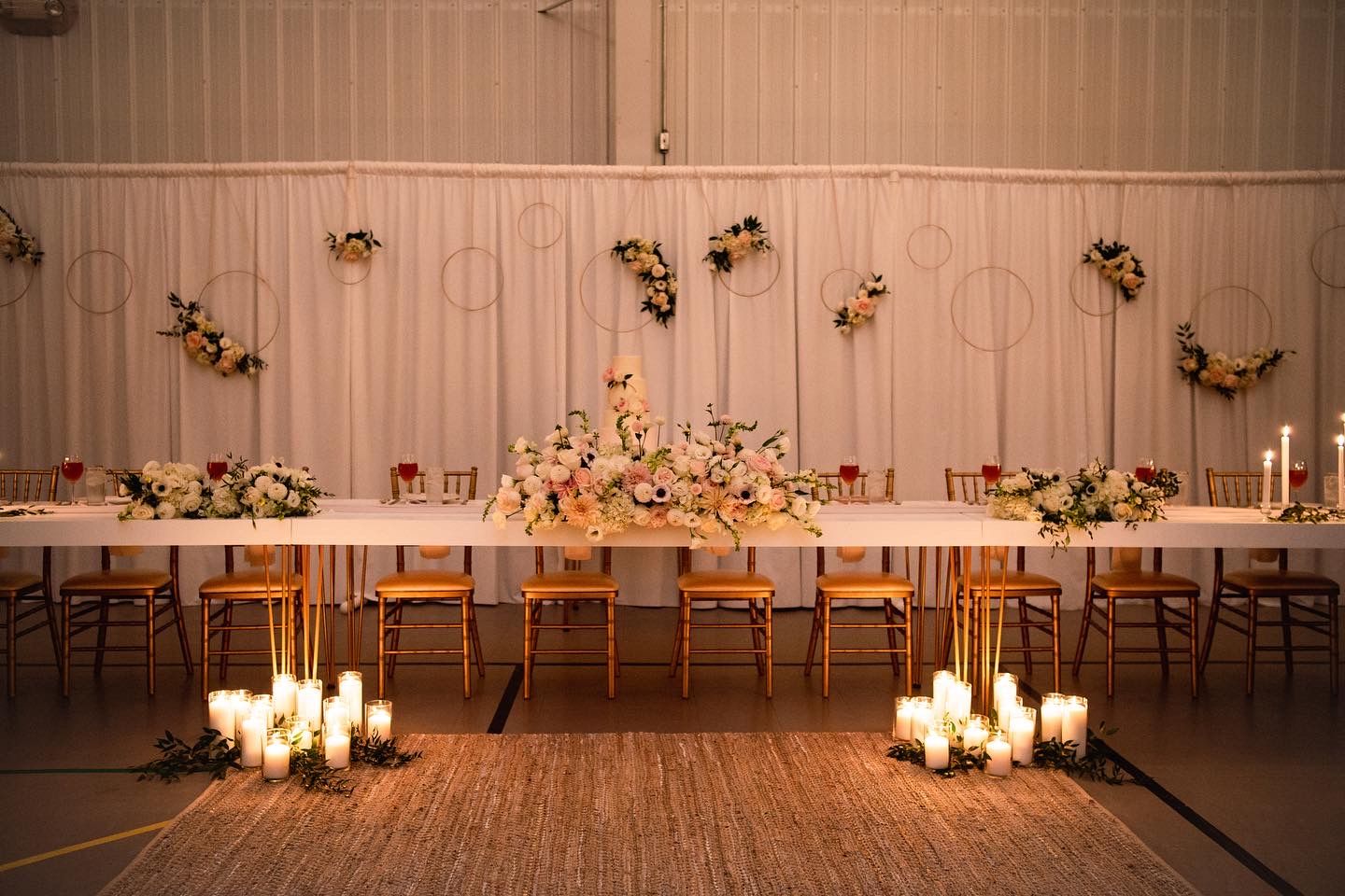Candlelit wedding reception setup with long tables and romantic floral arrangements in an indoor venue.