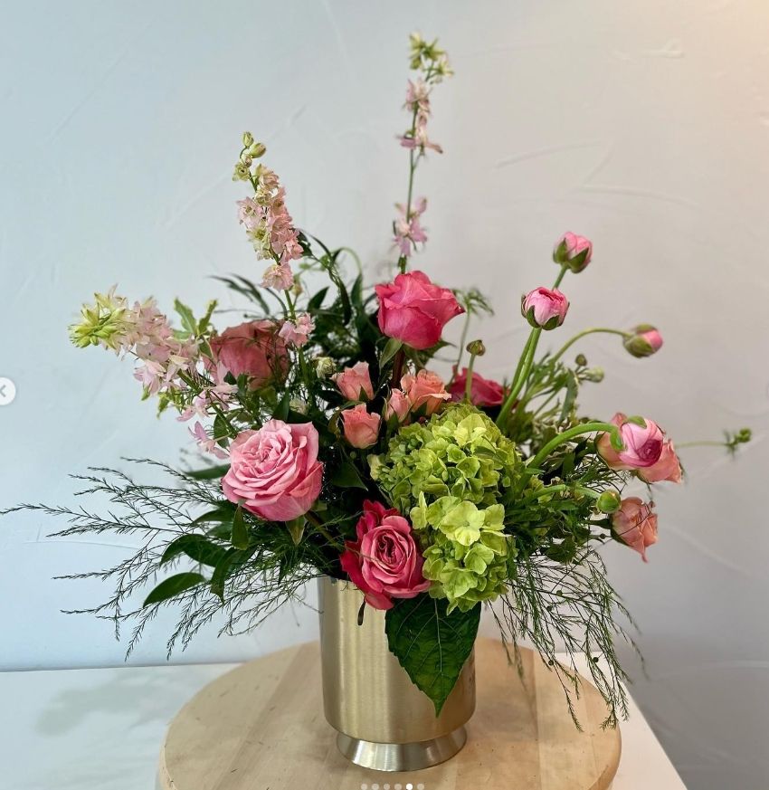 Fresh spring arrangement featuring pink roses, green hydrangeas, and delicate stems in a metallic vase.